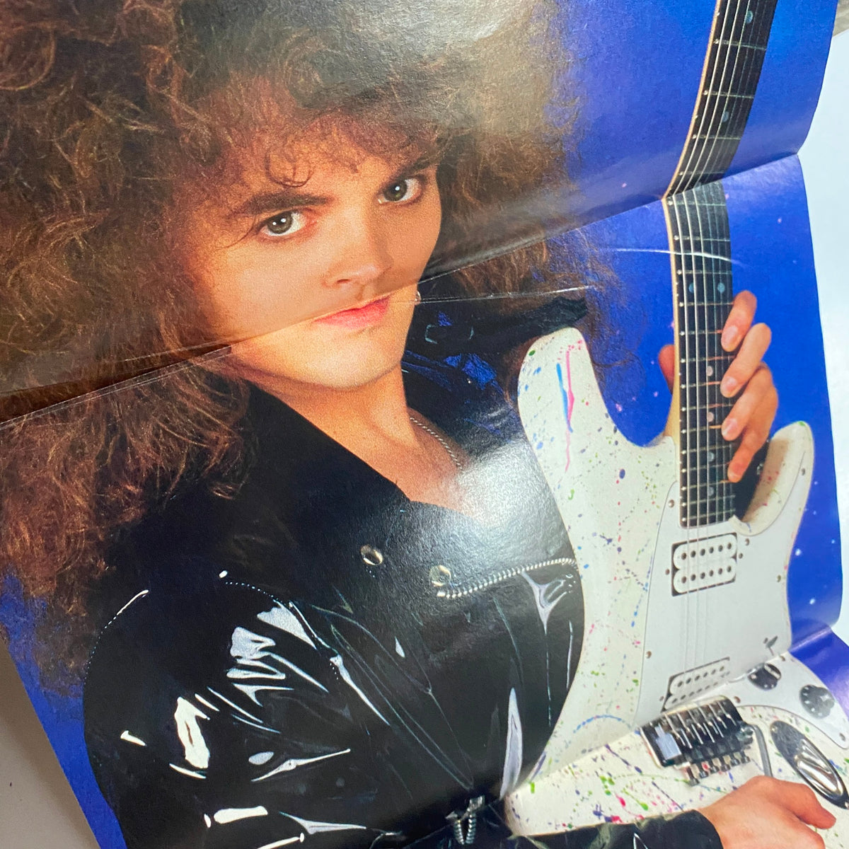 Image from Guitar for the Practicing Musician Magazine September 1988, showcasing a young guitarist with curly hair holding an artistic guitar, part of an eye-catching poster.
