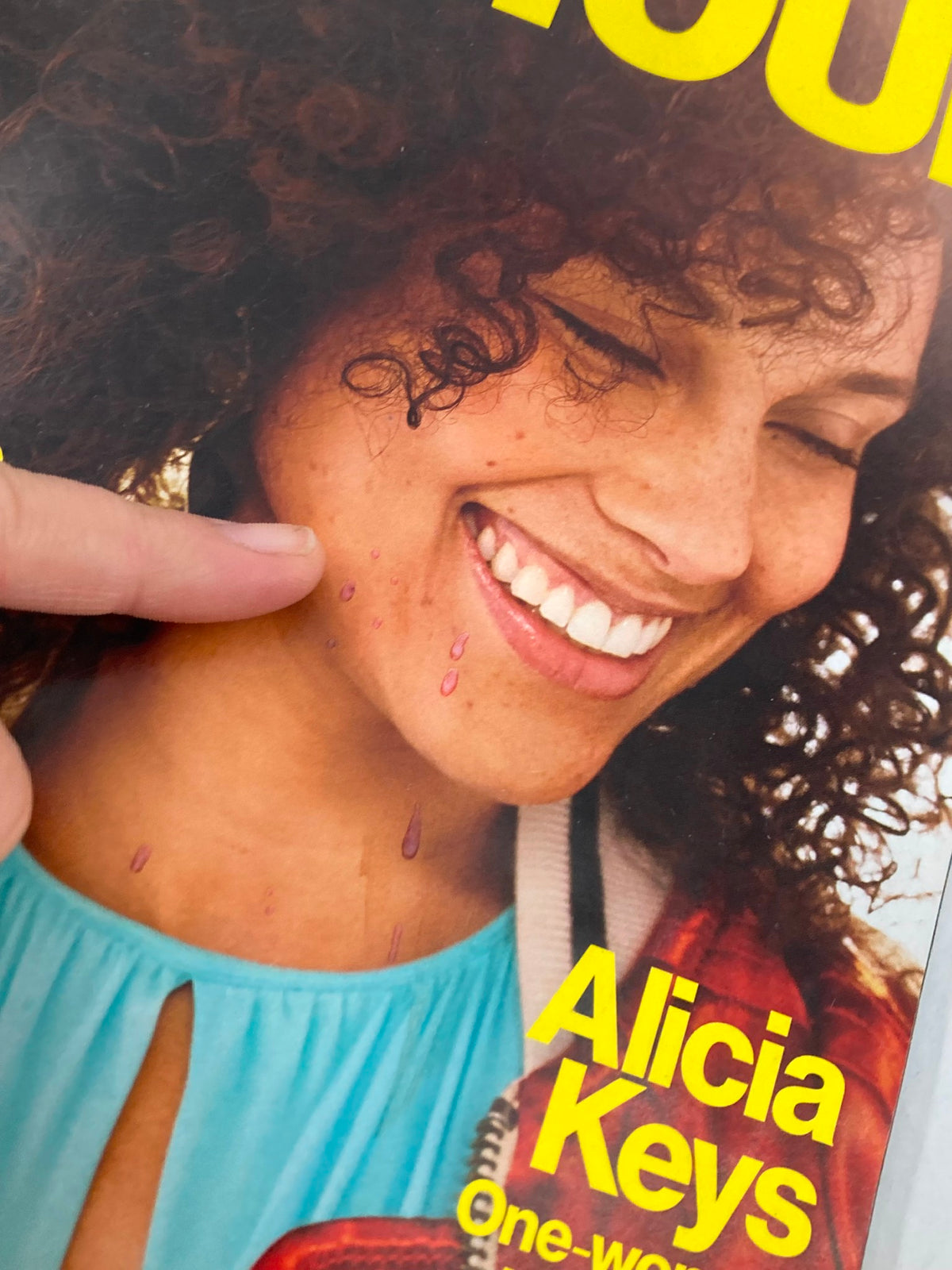 Close-up of Alicia Keys on the cover of Glamour Magazine March 2017, pointing at a detail on her face, showcasing the magazine's focus on authenticity and beauty.