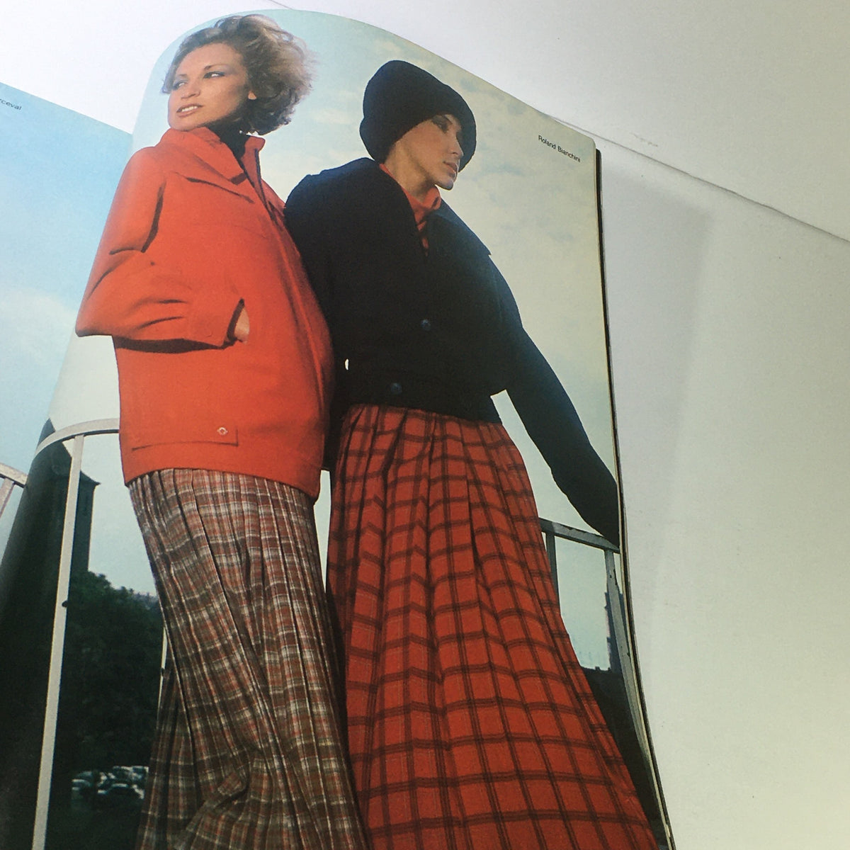 L'Officiel USA Magazine Fall Collection 1976 presenting two women modeling bold winter fashion with a striking red and a black outfit in an outdoor setting.