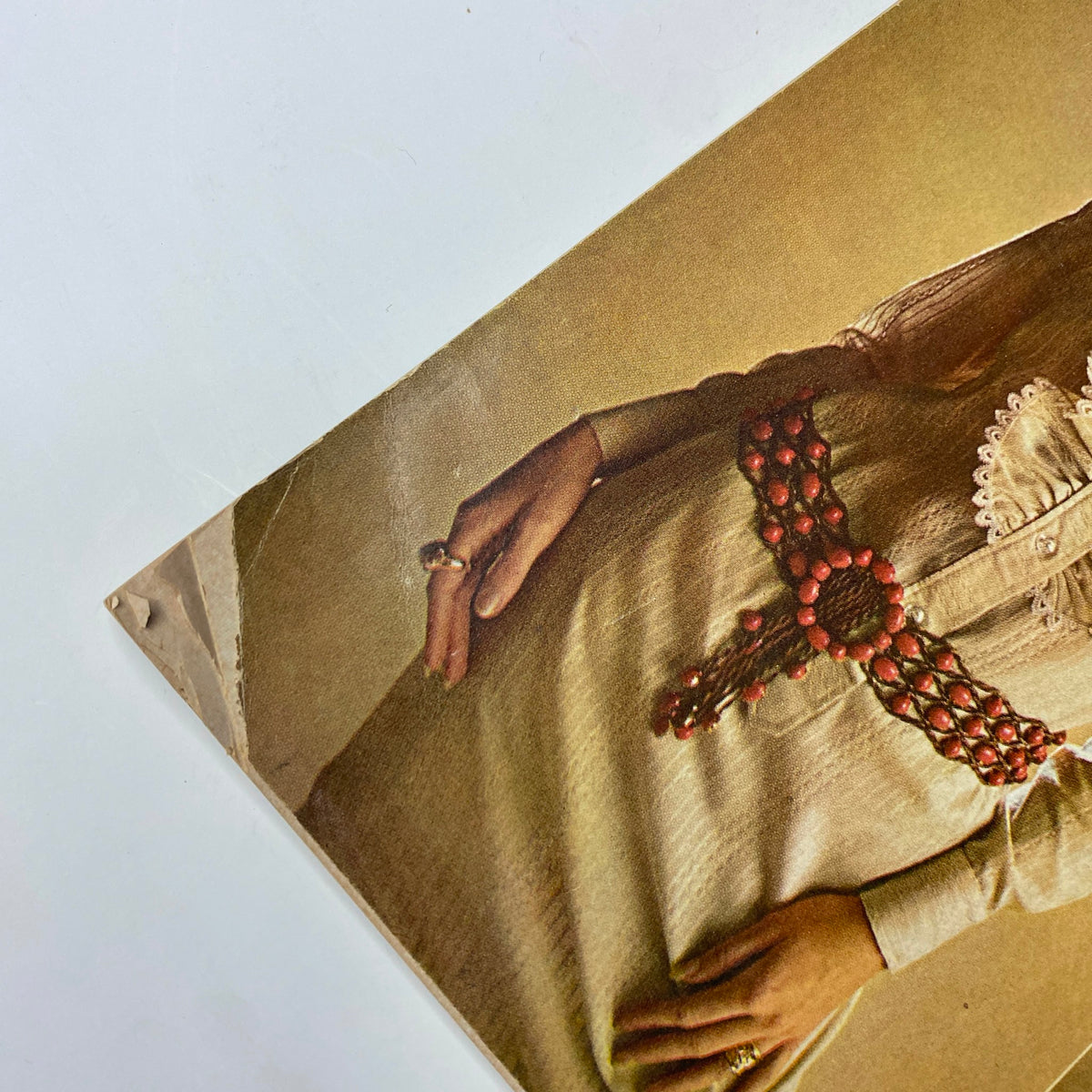 Close-up detail of a model wearing a vintage outfit featured in Vogue Magazine January 1, 1969, showcasing a red beaded belt and elegant attire, indicative of late 60s fashion.