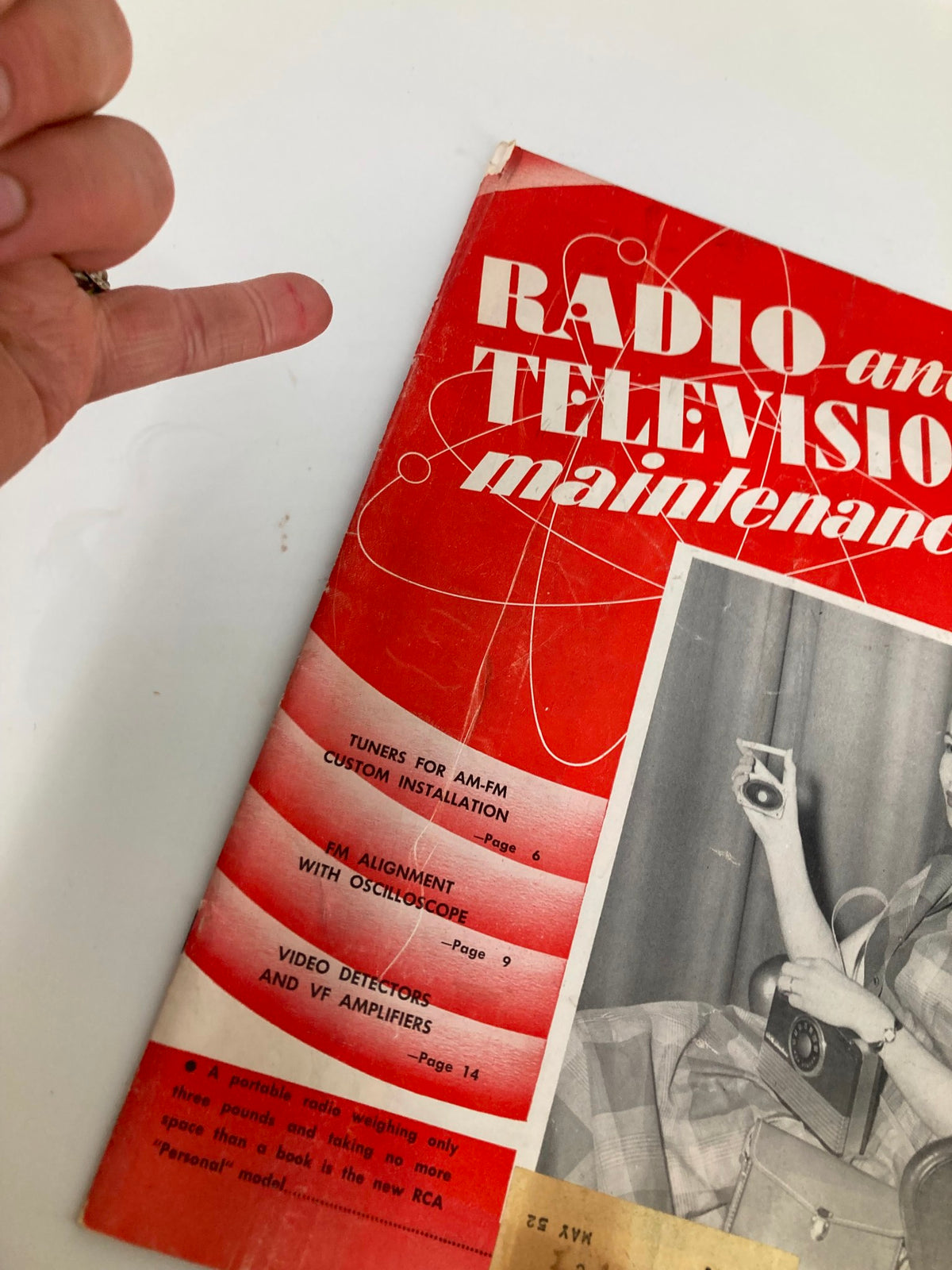 Detail view of the cover of VTG Radio and Television Maintenance June 1951 magazine, highlighting articles on FM alignment and radio maintenance, with a finger pointing to the page.