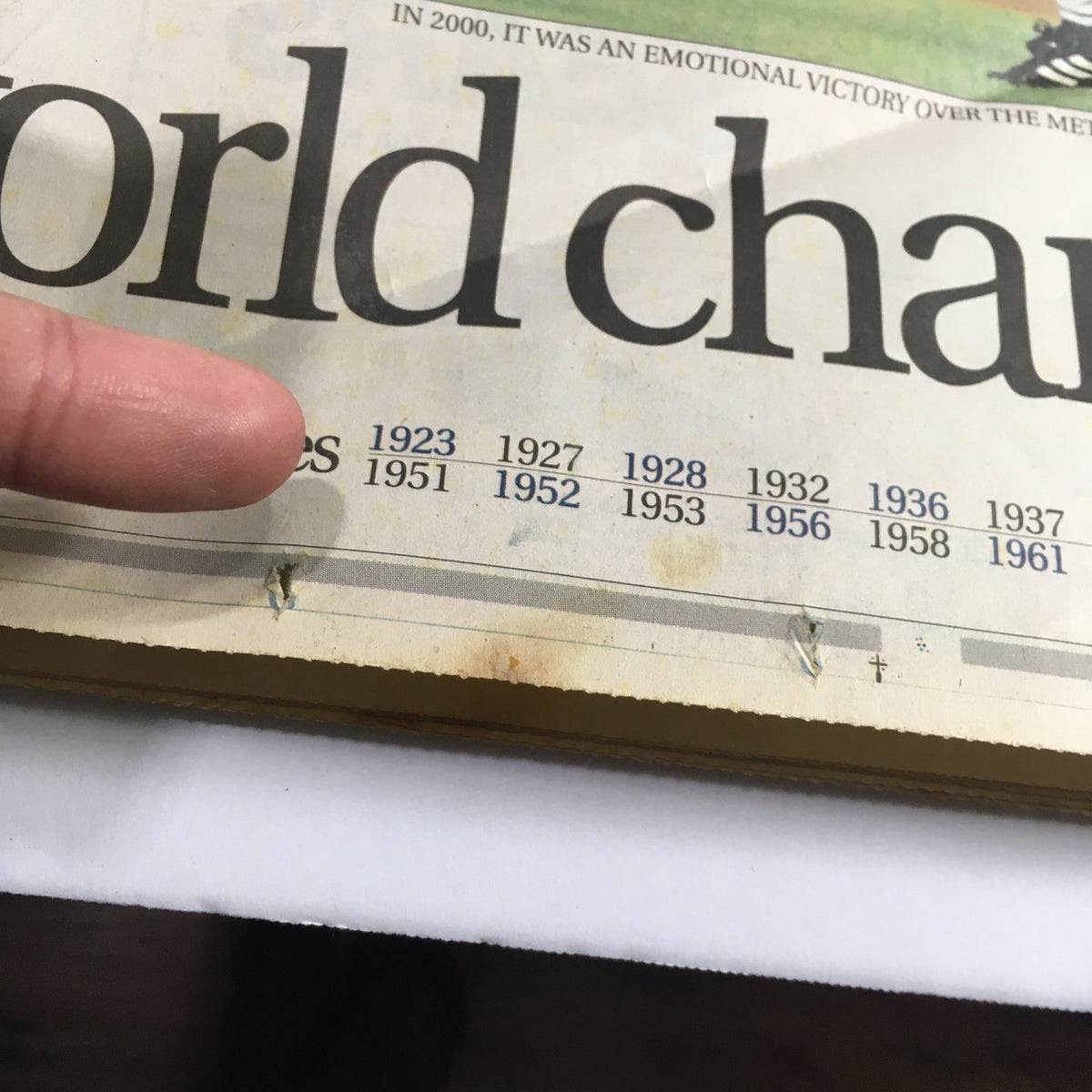 Close-up of The Star-Ledger Newspaper dated October 29, 2000, showing a timeline of years related to sports championships, with a finger pointing at the year 1951, contextualizing the legacy of sports victories.
