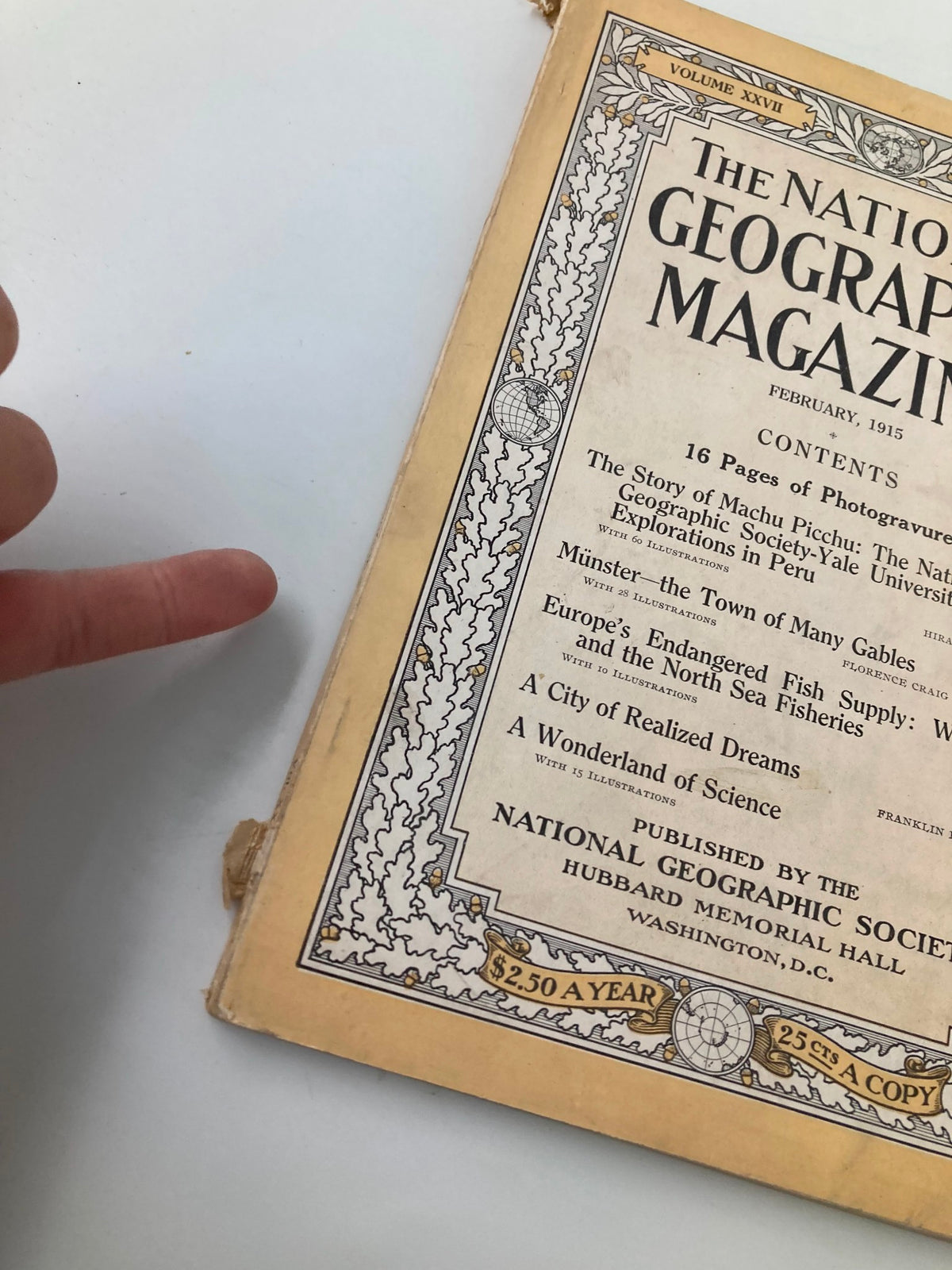 Close-up view of VTG The National Geographic Magazine February 1915 highlighting the edge and binding with a finger pointing at it.