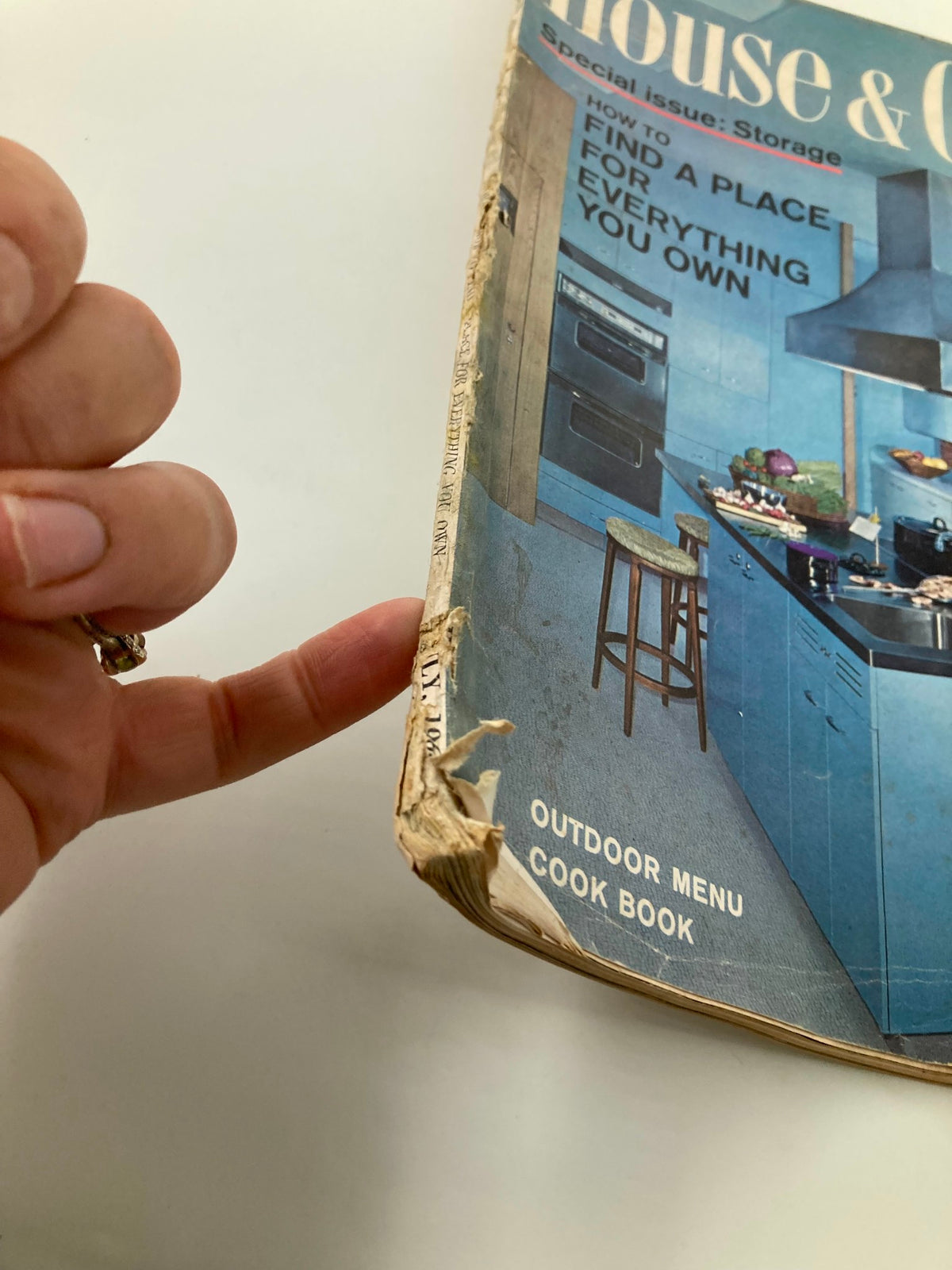 Side view of the damaged cover of VTG House & Garden Magazine July 1965, emphasizing wear and tear, while displaying the magazine's title and focus on organization.