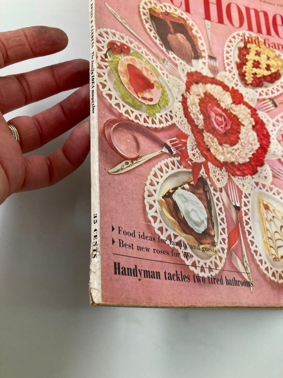 Side view of the VTG Better Homes & Gardens Magazine February 1959 displaying the spine and a glimpse of the cover art that highlights food ideas and the article 'Handyman tackles two tired bathrooms.'
