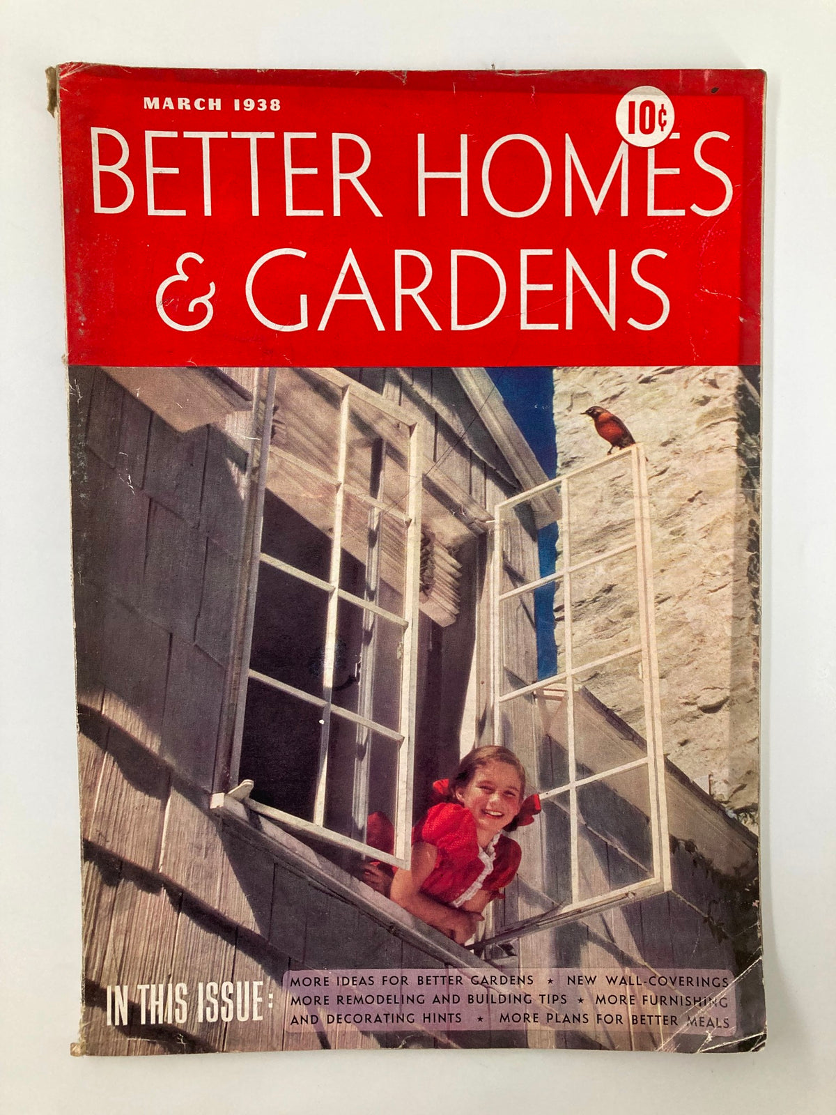 Cover of VTG Better Homes & Garden Magazine March 1938 featuring a girl in a red dress looking out of a window, emphasizing furnishing and decorating tips.