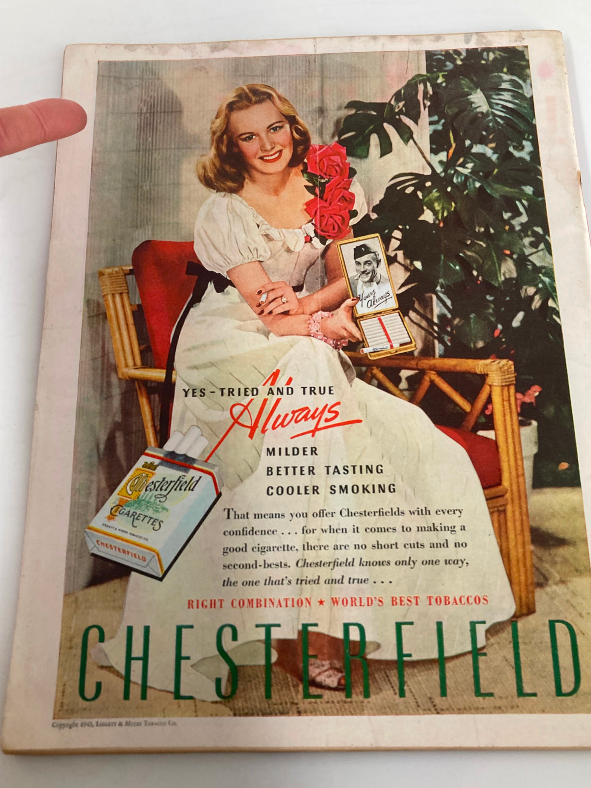 Back cover of a vintage advertisement for Chesterfield cigarettes featuring a smiling woman in a vintage dress, promoting a cooler smoking experience.