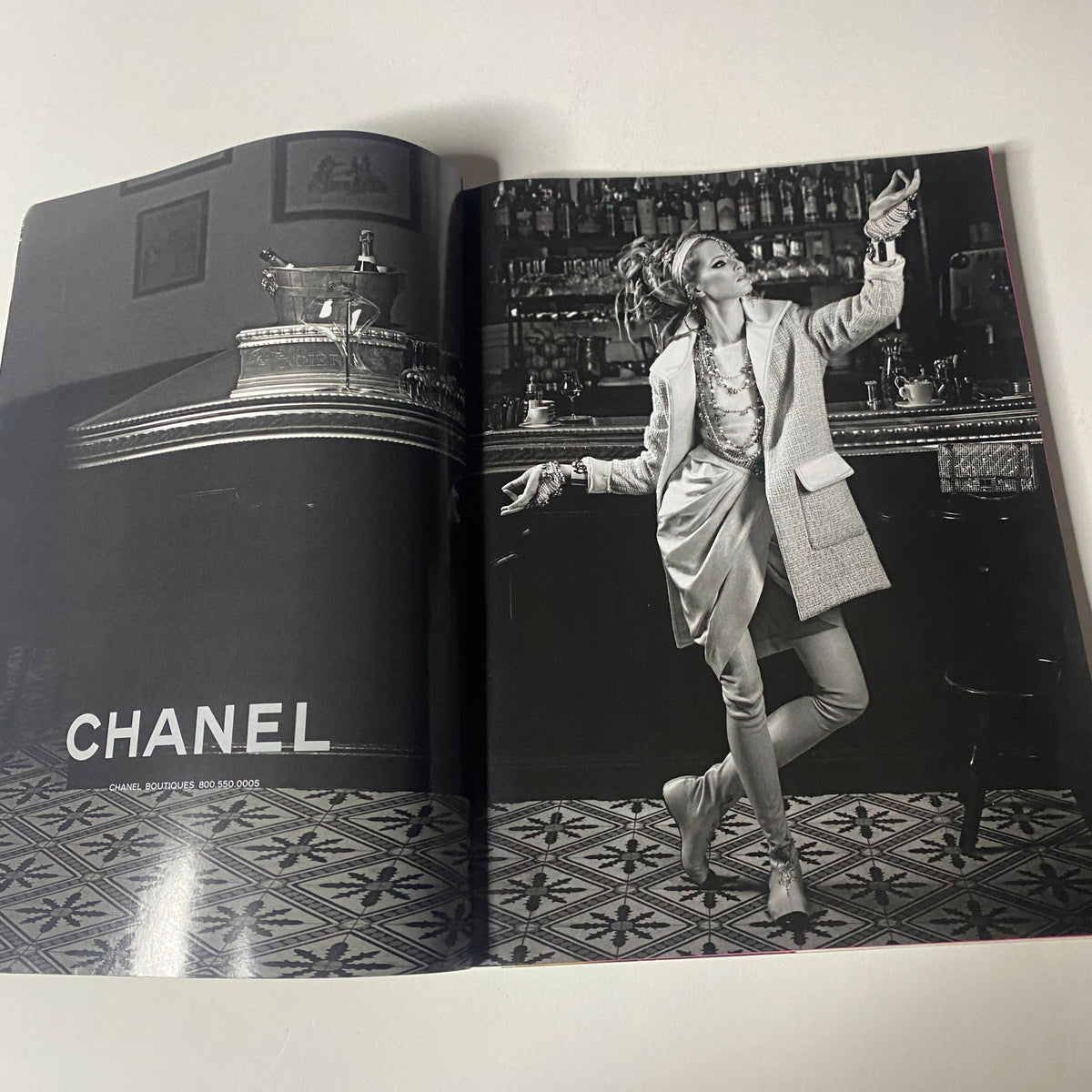 Vogue Magazine June 2012 presenting a Chanel advertisement with a model in a chic outfit dancing in a vintage bar setting. The photograph emphasizes high fashion in a sophisticated ambiance.