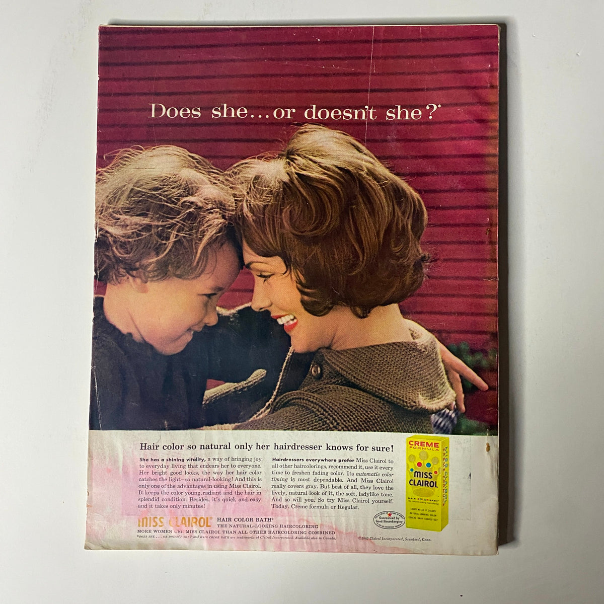 Back cover of Harper's Bazaar Magazine December 1960 featuring an advertisement with a mother and child, asking 'Does she...or doesn't she?' emphasizing hair color.