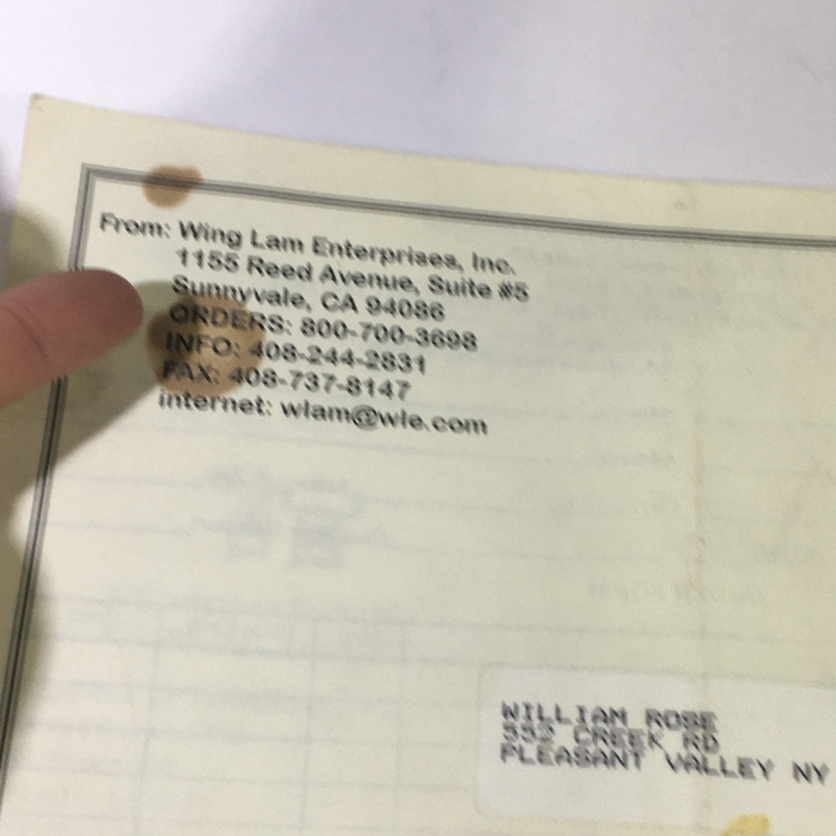 Image of the back cover of the Wing Lam Enterprises Inc. Mail Order Catalog Spring 1995, displaying contact information and a finger pointing at the details.