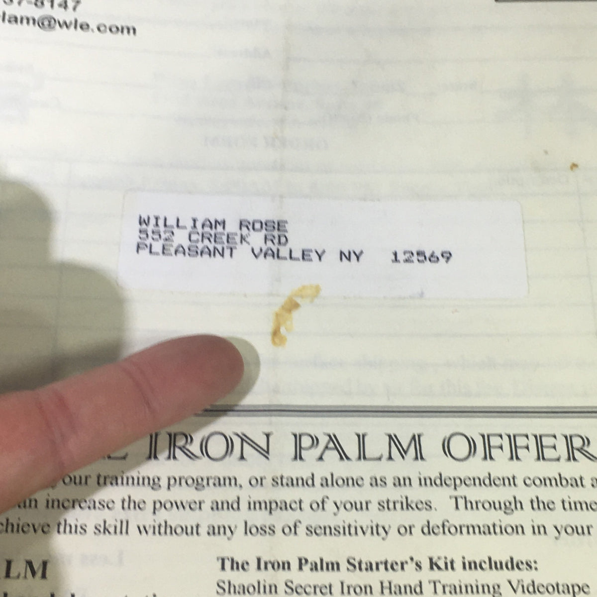 Close-up of the address label on the back of the Wing Lam Enterprises Inc. Mail Order Catalog Spring 1995, with a finger pointing at the recipient's information.