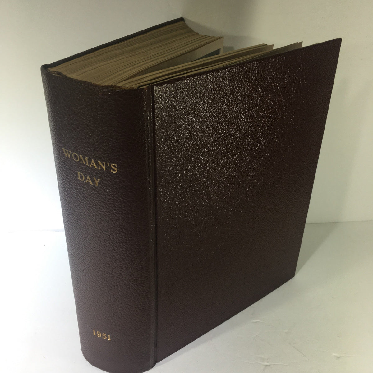 1951 Woman's Day Magazine Compilation showcasing the dark brown leather-bound cover with the title embossed in gold.