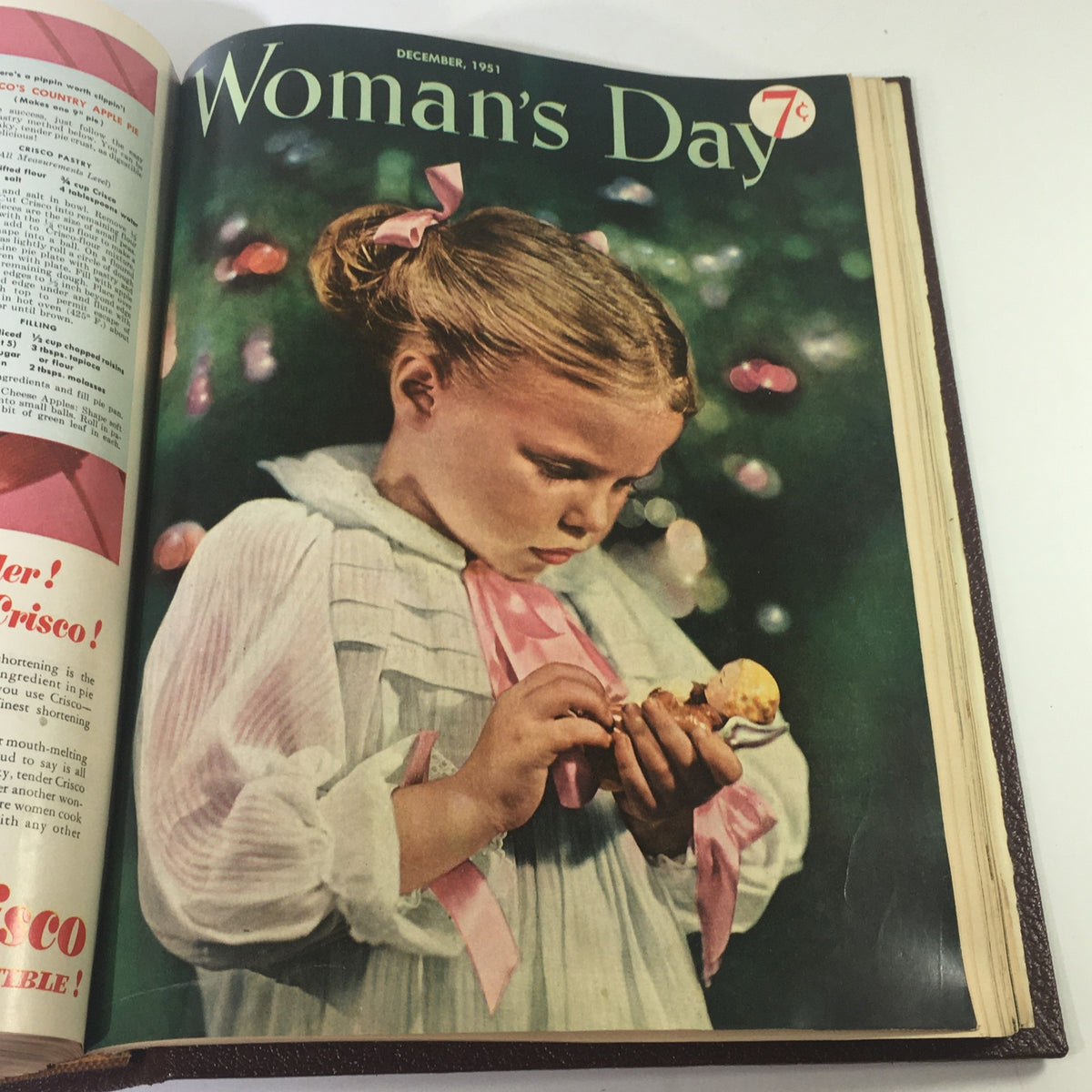 Cover page of the 1951 Woman's Day Magazine featuring a young girl in a white dress holding a doll, surrounded by festive decorations.