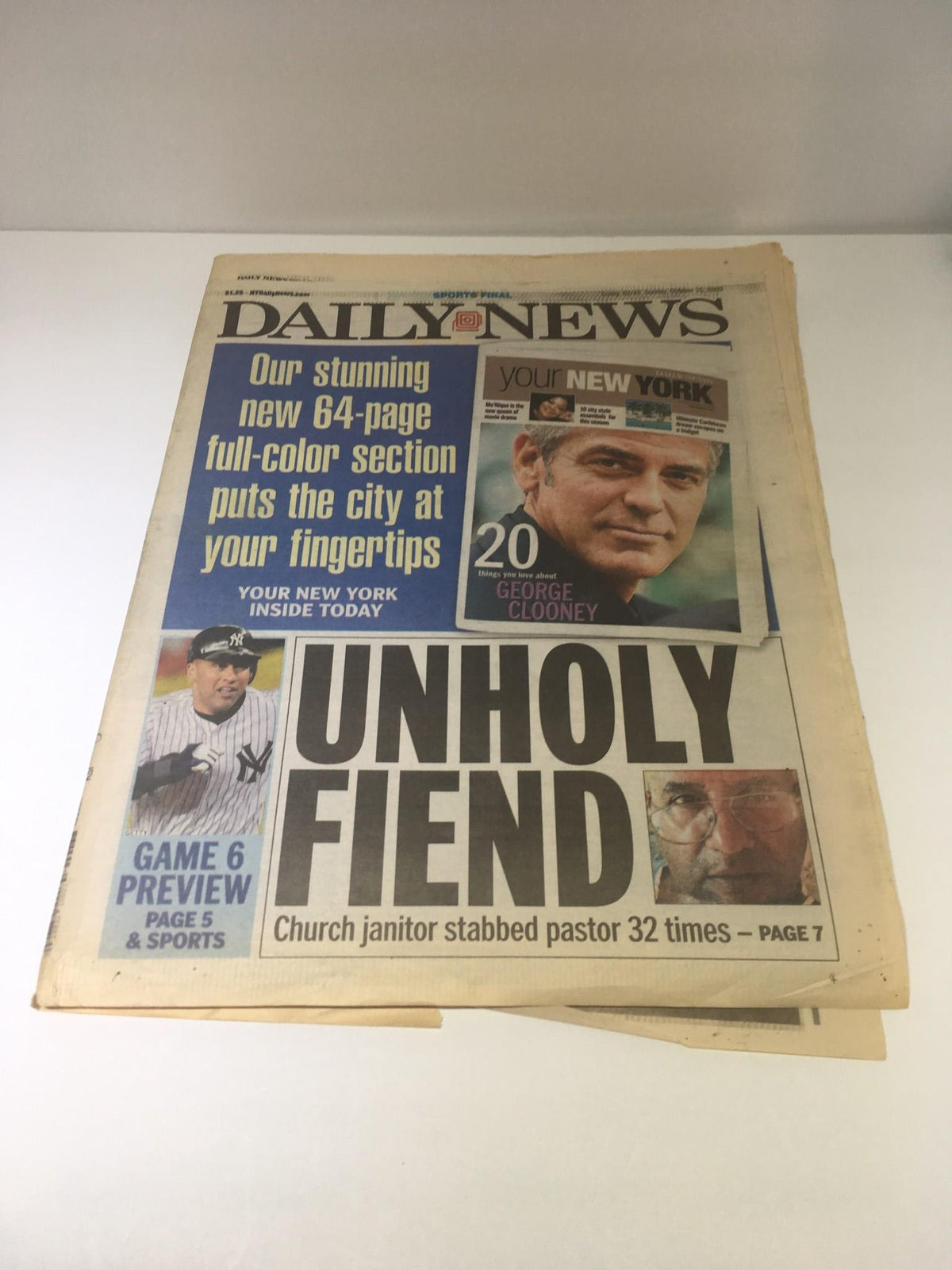 New York Daily News front page from October 25, 2009, featuring the headline "Unholy Fiend" with an image of George Clooney and a news story about a church janitor's crime.
