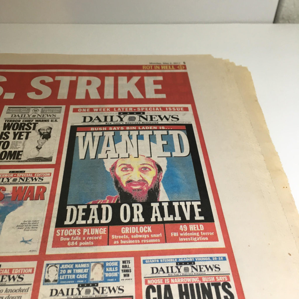 Close-up of a wanted poster from the NY Daily News, May 2, 2011, illustrating the headline 'WANTED DEAD OR ALIVE' related to Osama Bin Laden, alongside other news elements.