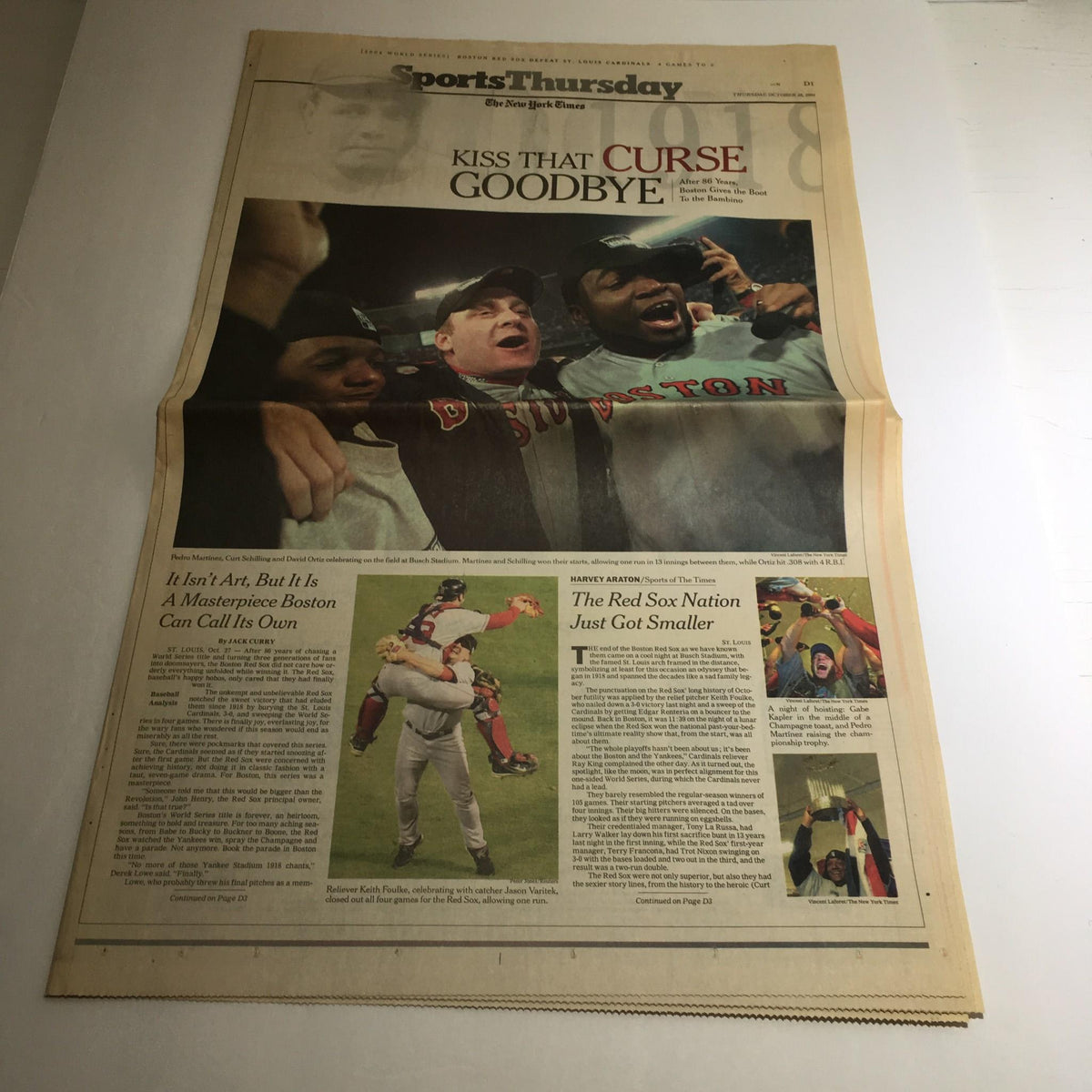 Image of The New York Times issue from October 28, 2004, featuring the headline 'Kiss That Curse Goodbye,' showcasing a memorable moment in sports history with jubilant Boston Red Sox players celebrating.