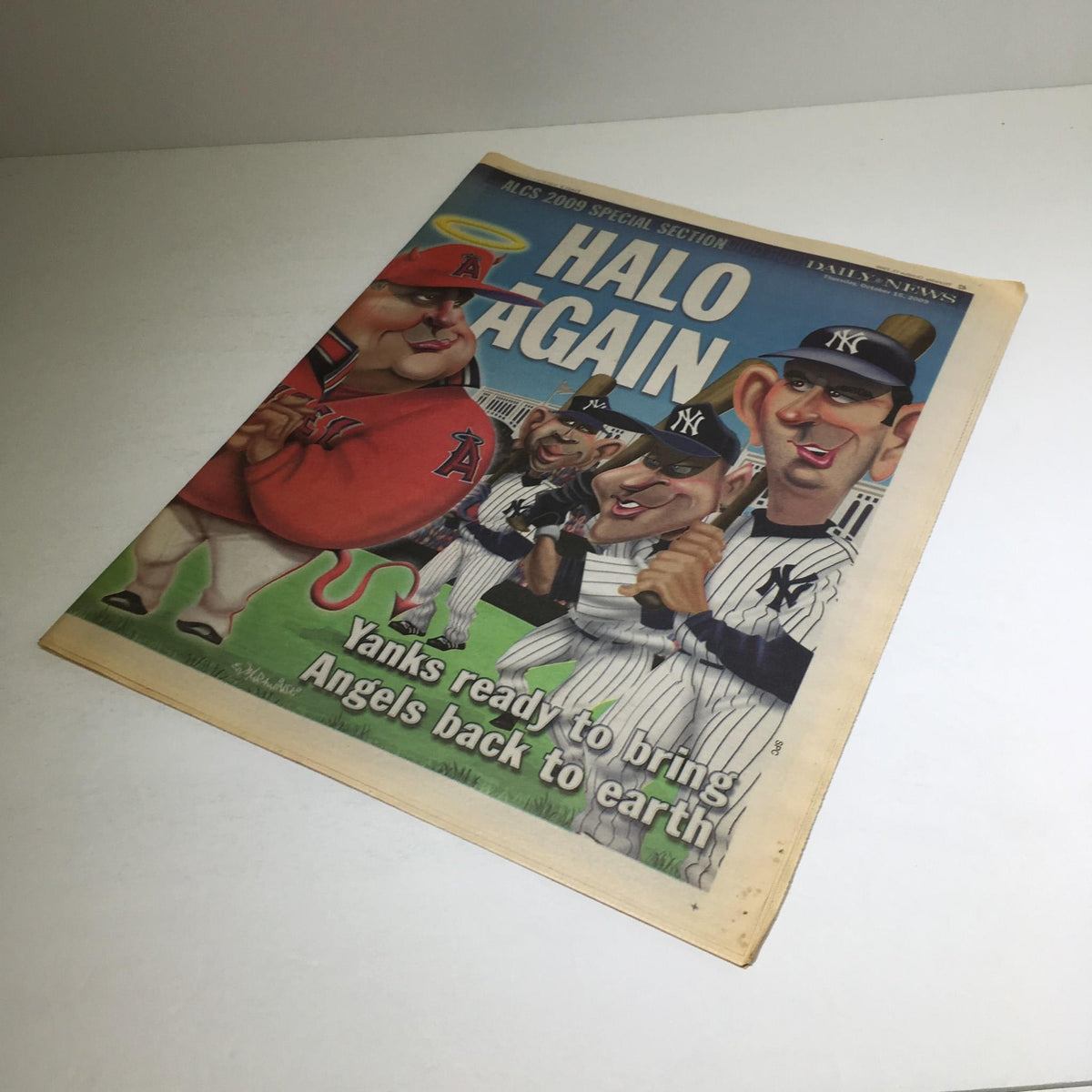 Vintage NY Daily News cover from 10/15/2009 titled 'Halo Again: Yanks Ready to Bring Angels Back to Earth', featuring cartoon illustrations of baseball players.