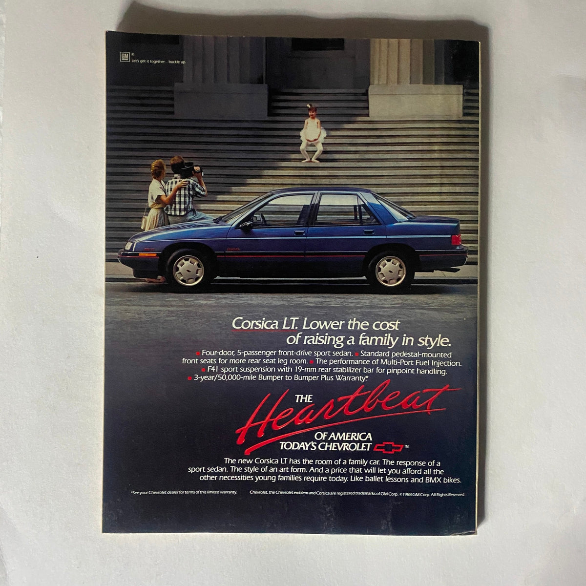 Chevrolet Corsica advertisement from the late 1980s showcasing a blue sedan with a family on the steps, highlighting affordable family car features.