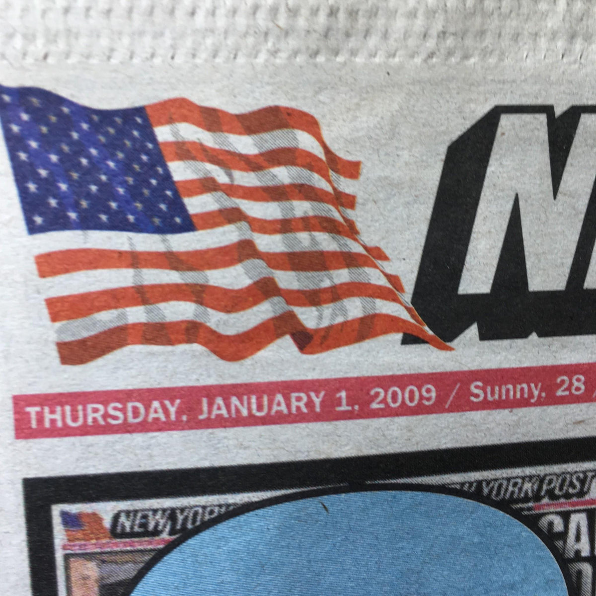 Detail of the New York Post newspaper dated Thursday, January 1, 2009, showing an American flag and date, signifying New Year celebrations.