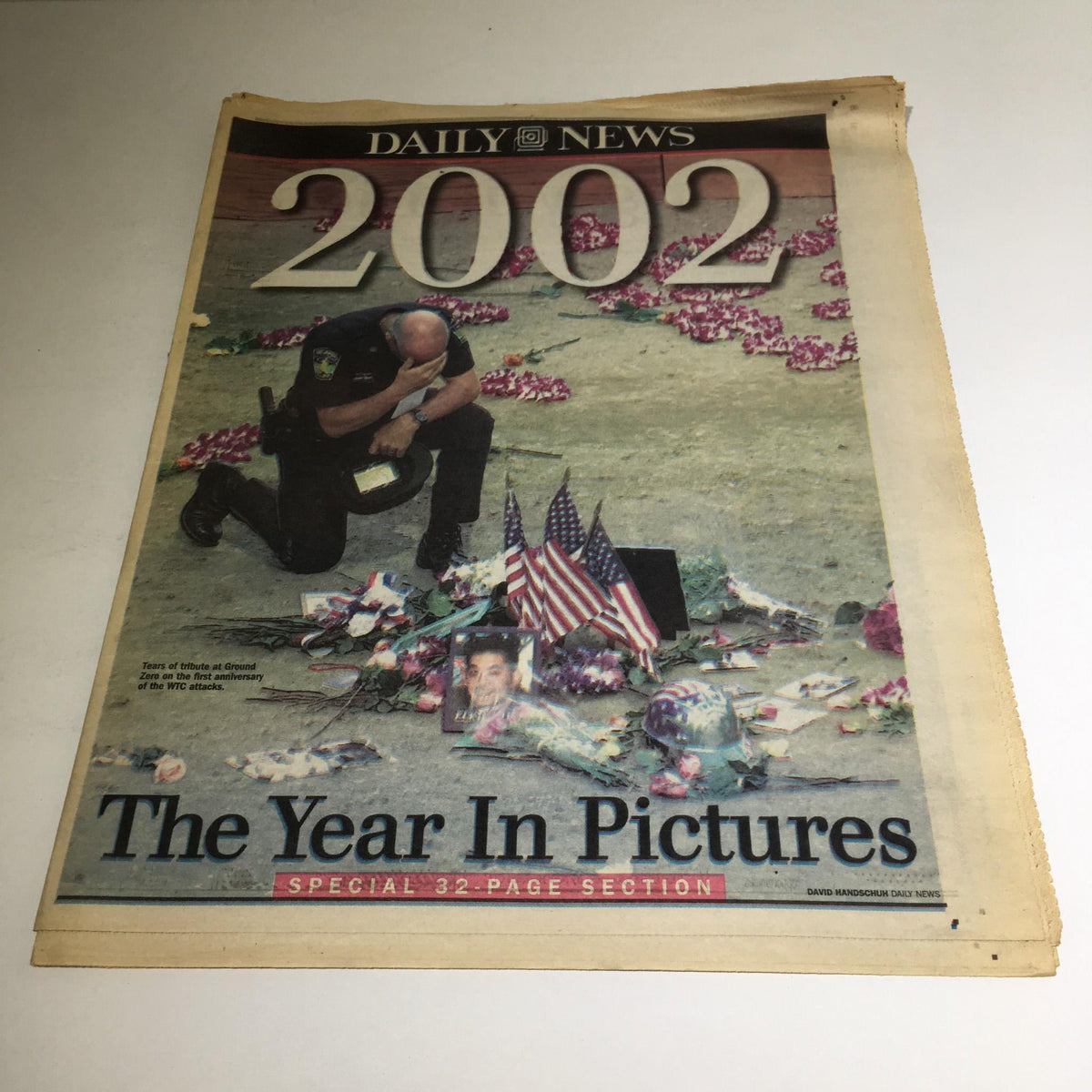 Cover of New York Daily News: December 29, 2002, The Year in Pictures featuring a police officer kneeling on a floral tribute.