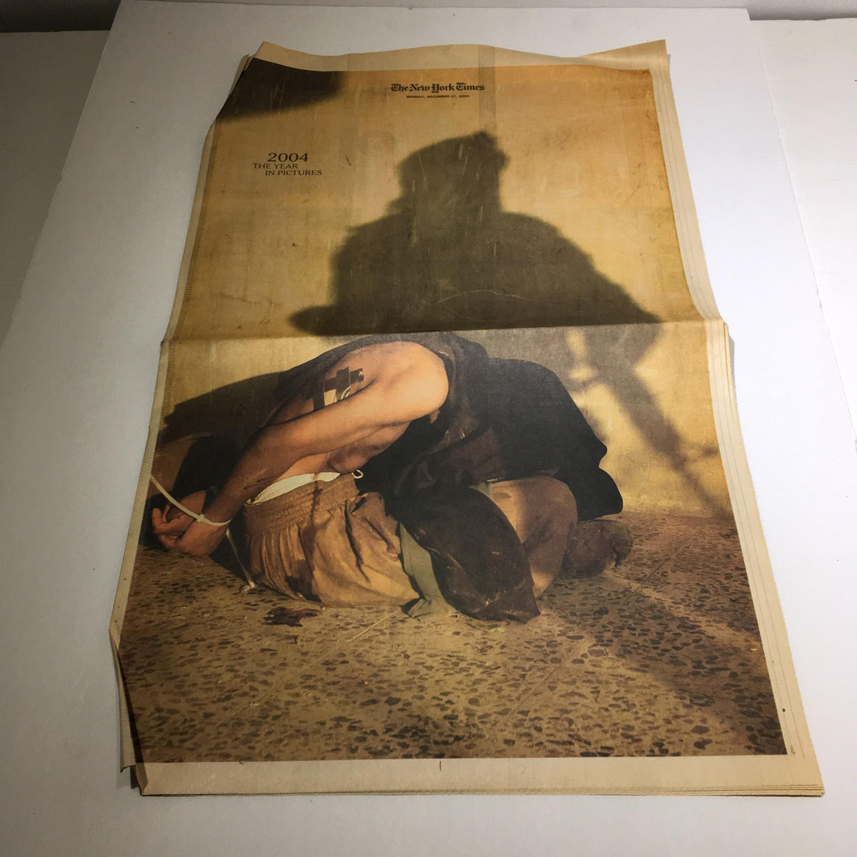 The New York Times: Dec 27 2004, 2004 The Year in Pictures, featuring a powerful image depicting a person in a poignant moment, emphasizing the emotional weight of the year.