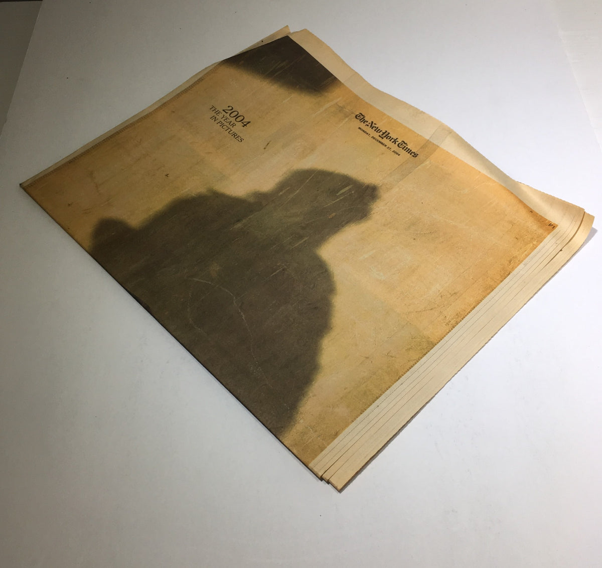 The New York Times: Dec 27 2004, 2004 The Year in Pictures, displaying a cover image with a blurred silhouette, representing the themes of reflection and memory from the year.