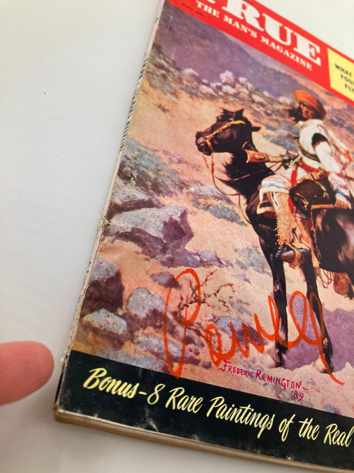 Close-up view of the cover of TRUE The Man's Magazine May 1954 showing details of the illustration and the signature of Frederic Remington, emphasizing the magazine's vintage appeal.