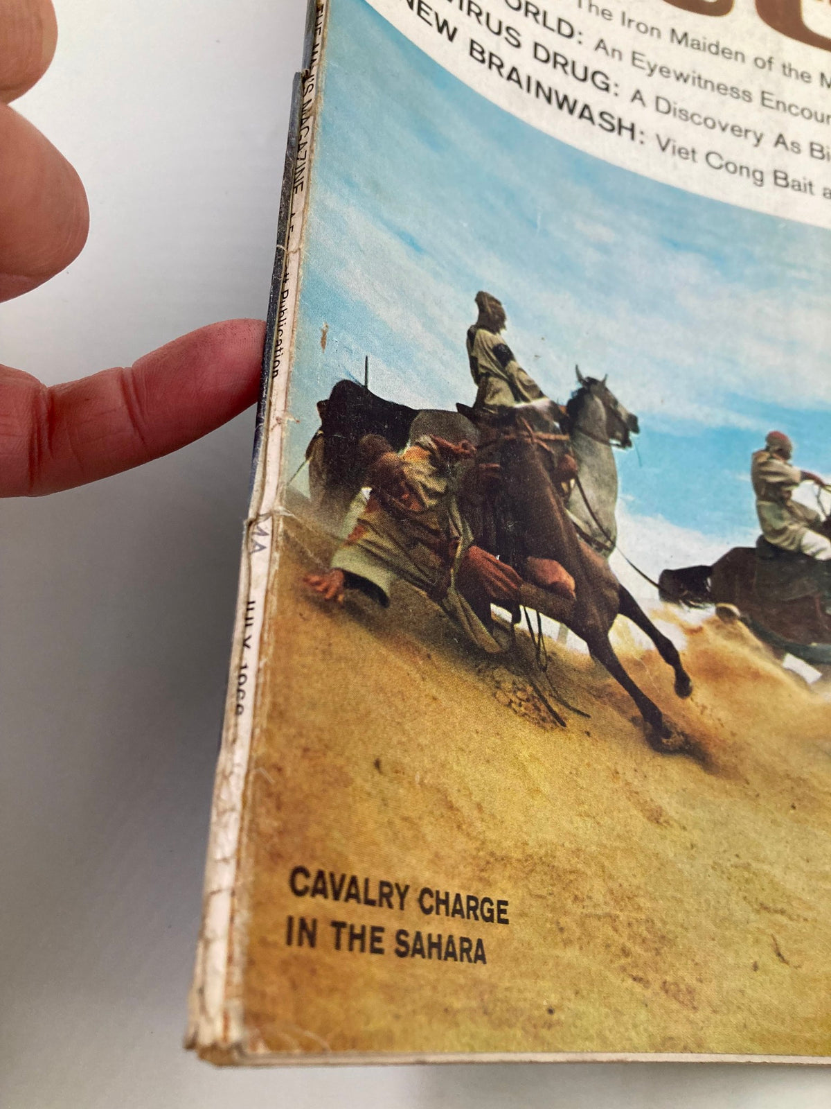 Close-up of the spine and cover details of TRUE The Man's Magazine July 1966, highlighting the title 'Cavalry Charge in The Sahara' and signs of wear for collectors.