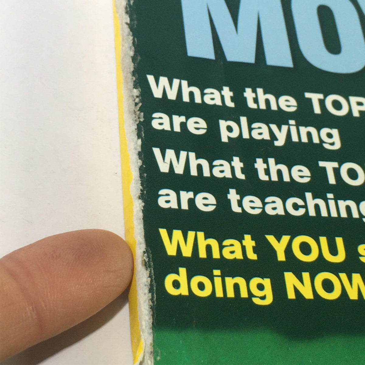 Close-up view of the edge of the February 2000 Golf Magazine featuring David Duval, Tiger Woods, Ernie Els, and Webb Simpson, highlighting minor wear and tear with visible finger pointing at the edge.