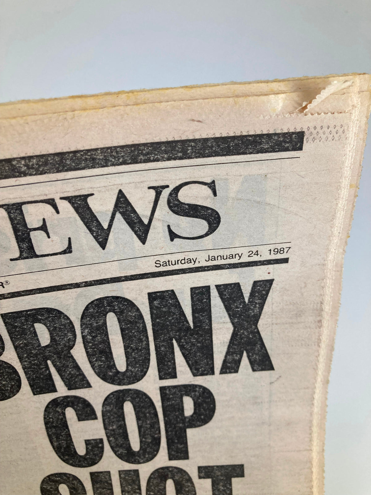 Close-up view of the VTG Daily News Newspaper from January 24, 1987, highlighting the date and the dramatic headline 'BRONX COP SHOT DEAD.' Minor wear visible on the newspaper.