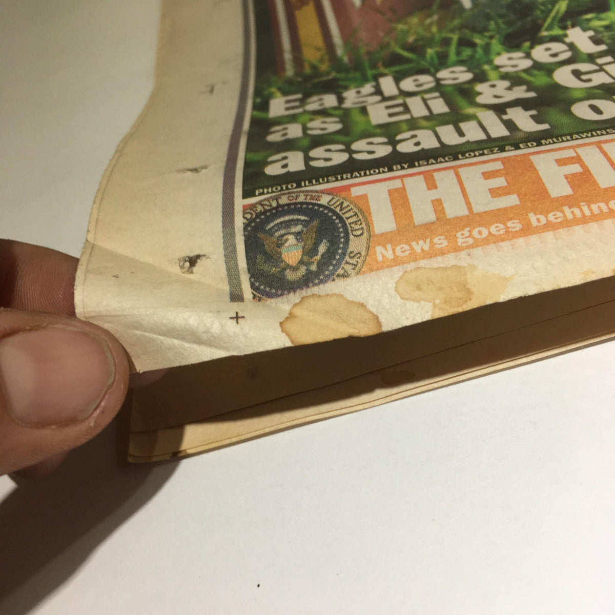Detail of the New York Daily News from Nov 9, 2008, showing the bottom edge with slight staining and an illustration featuring the Great Seal of the United States, highlighting historical significance.