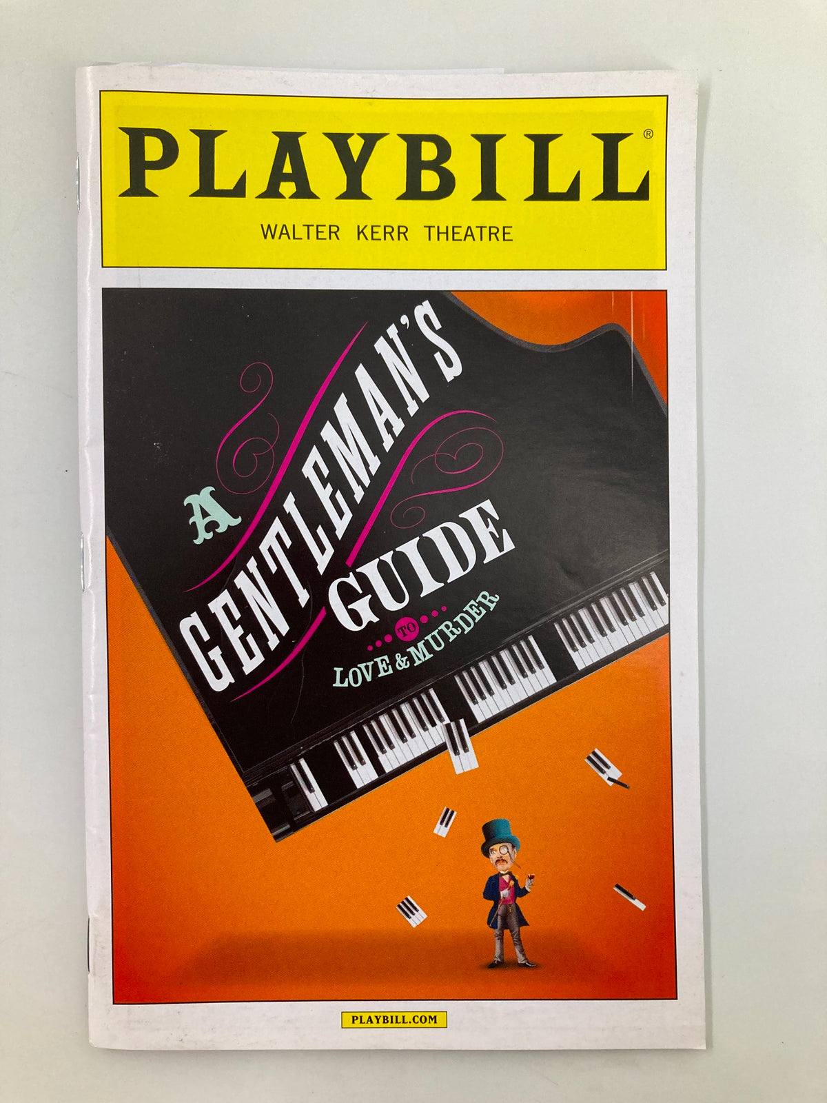 Cover of the 2014 Playbill for A Gentleman's Guide To Love & Murder at the Walter Kerr Theatre, featuring vibrant graphics and a piano motif.