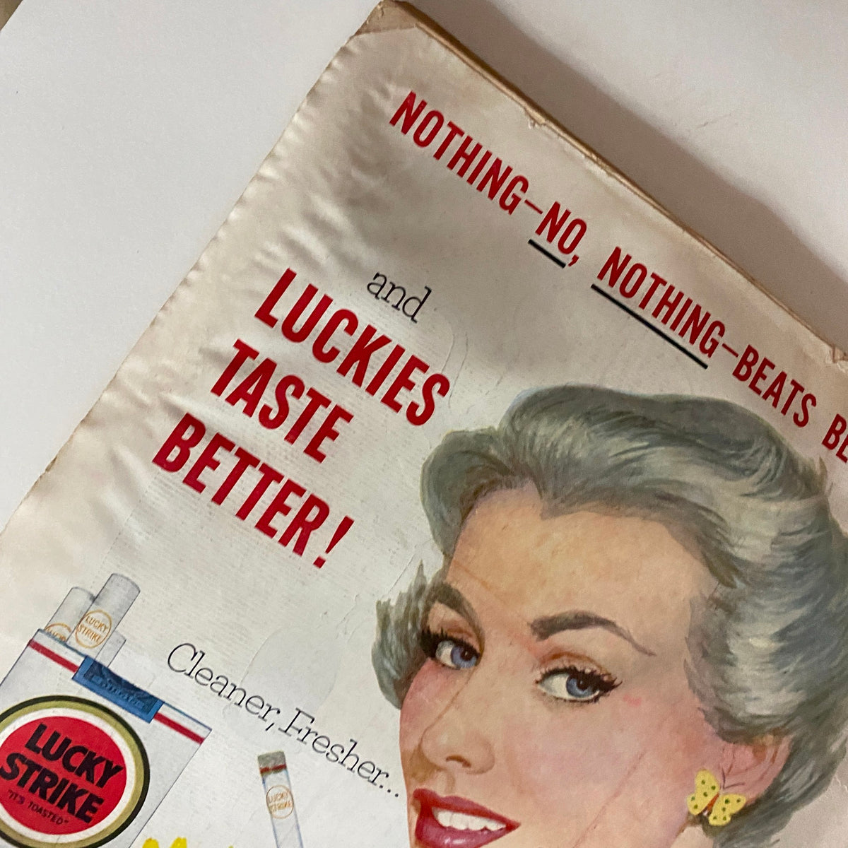 Detail of a Lucky Strike cigarette advertisement in VTG Time Magazine April 6, 1953, showcasing a woman with a cigarette and the slogan 'Luckies taste better!'.