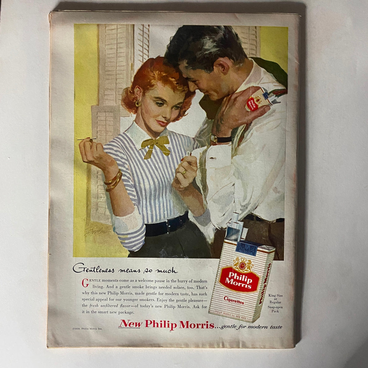 Vintage advertisement featuring a couple, promoting New Philip Morris cigarettes, with the tagline 'Gentleness means so much.' The ad highlights the modern taste appeal of the product, and is illustrated in a colorful, mid-20th century style, showcasing a nostalgic moment related to the VTG Time Magazine February 13, 1956, Vol 67 No. 7 Juscelino Kubitschek.