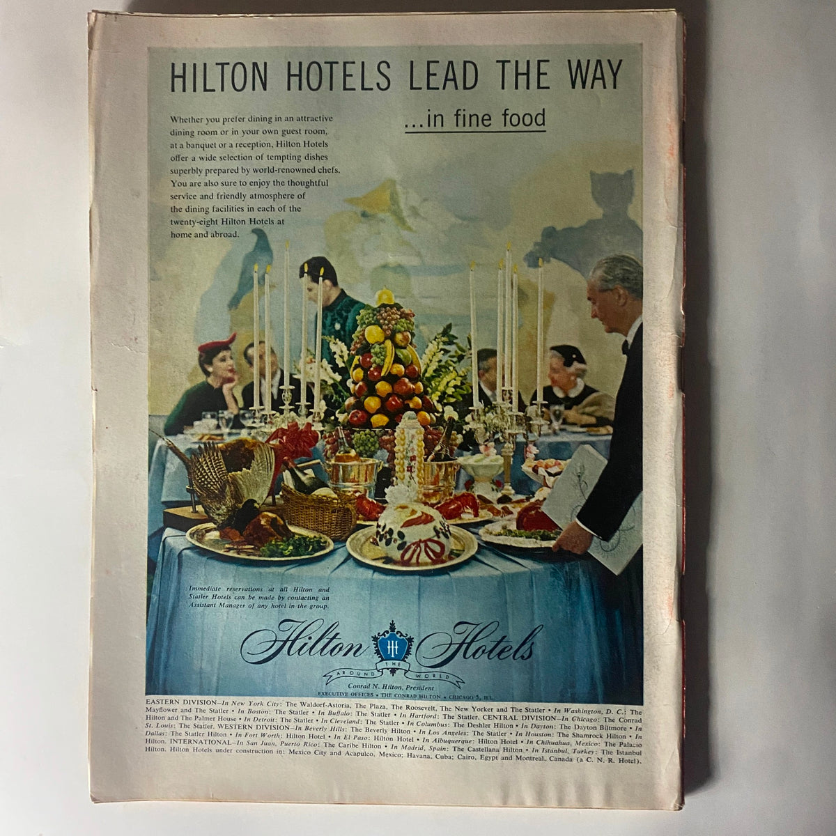 Advertisement for Hilton Hotels featured in the vintage Time Magazine March 19, 1956, showcasing elegant dining setups and fine food in a luxurious atmosphere.