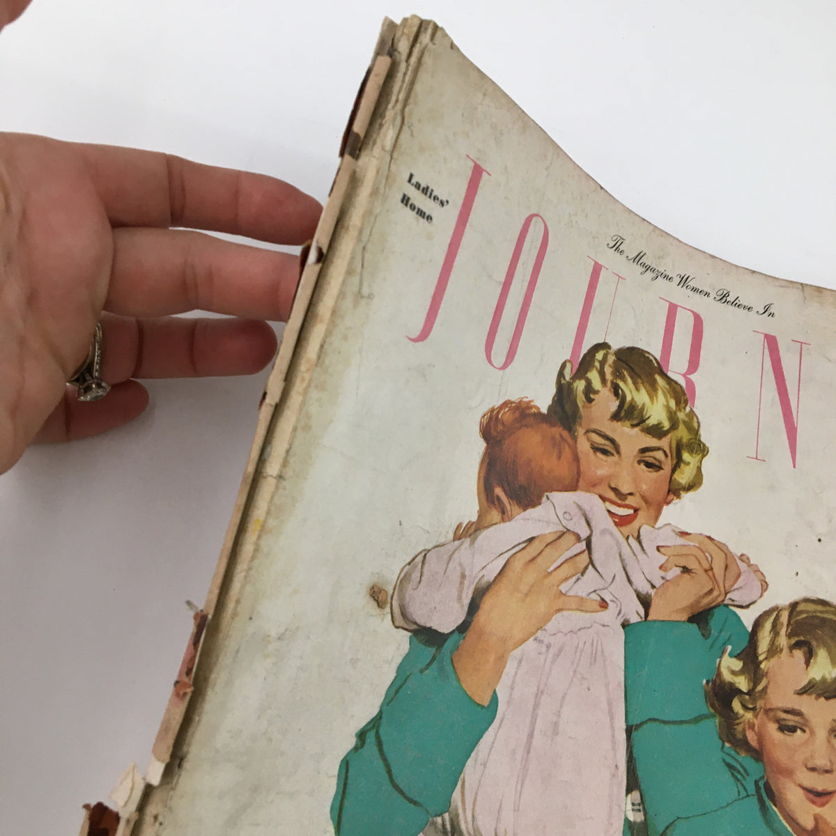 Close-up of the cover of Ladies' Home Journal Magazine December 1948, featuring an illustration of a woman holding a child, with evident wear on the binding.