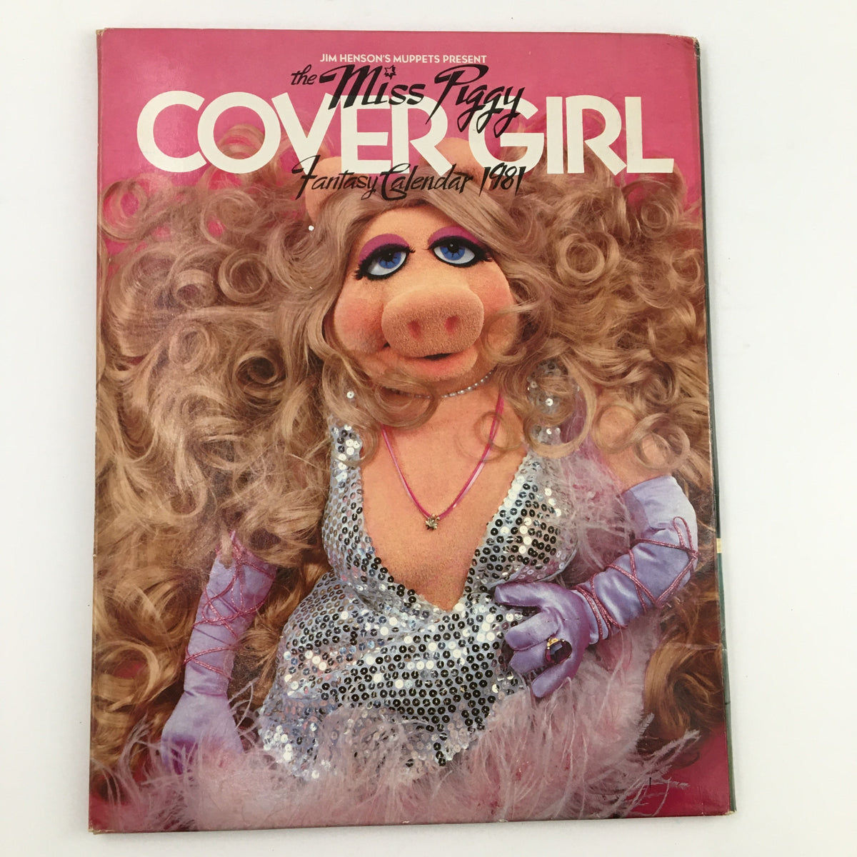 Cover of Jim Henson's Muppets Present The Miss Piggy Cover Girl Fantasy Calendar 1981 featuring Miss Piggy in glamorous attire, sparkling dress with curly blonde hair, striking a confident pose.