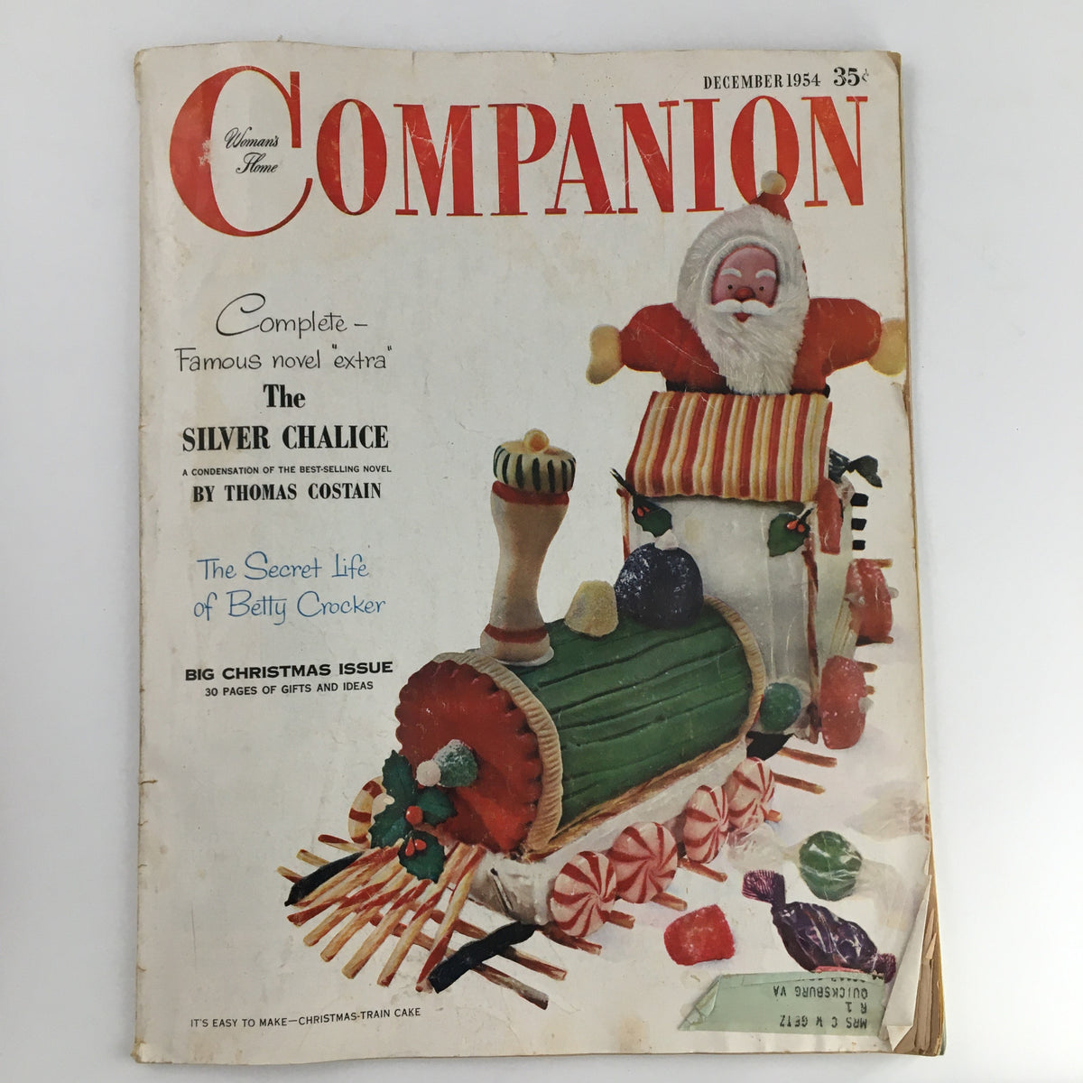 Cover of Women's Home Companion Magazine December 1954 featuring a festive Christmas theme, promoting the cover story 'The Silver Chalice' by Thomas Costain, with a colorful candy train and Santa Claus.