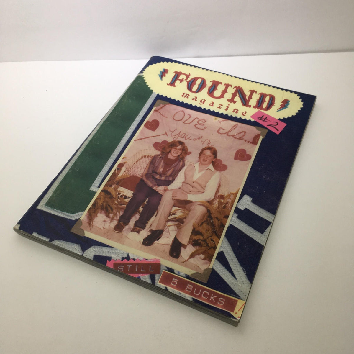 Cover of Found Magazine #2 showcasing a nostalgic photograph with handwritten notes, reflecting the essence of human experiences and collectibles in vintage magazines.