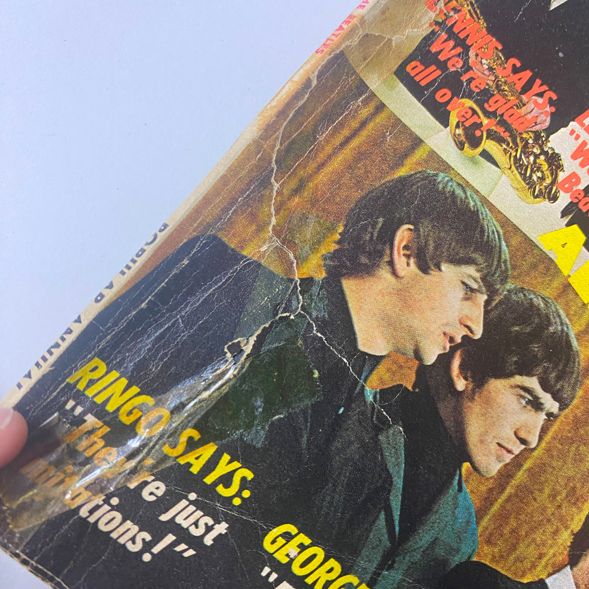 Close-up of the cover of Popular Annual Magazine September 1964, featuring images of Ringo Starr and George Harrison from The Beatles, with damaged edges emphasizing its vintage condition.