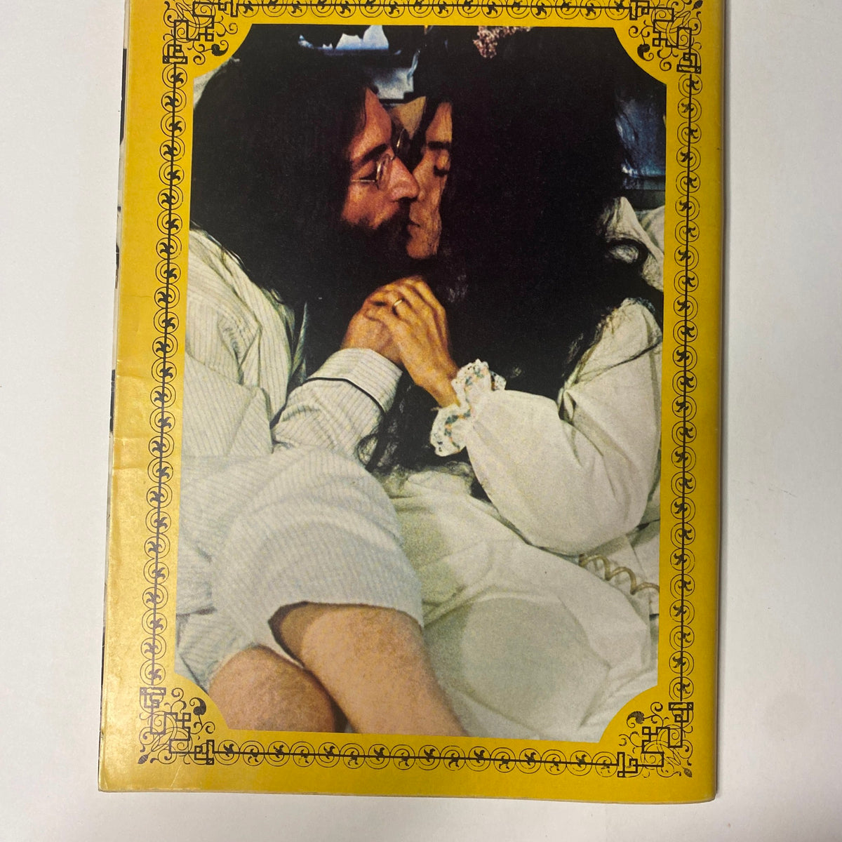 John Lennon and Yoko Ono share a tender kiss in this intimate photo from the 'Beatles Special John Lennon and Yoko Ono: Their Love Book Collector's Edition.' The image highlights their deep affection for one another, reflecting their influential partnership and creative journey.