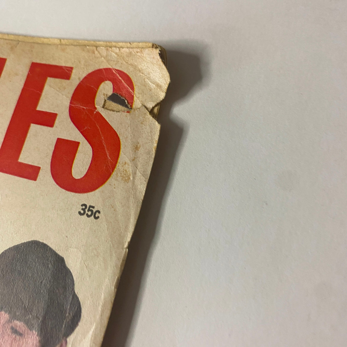 Detail view of the upper section of the 1963 Meet The Beatles magazine cover, showcasing the red letters on the title and wear consistent with vintage publications.