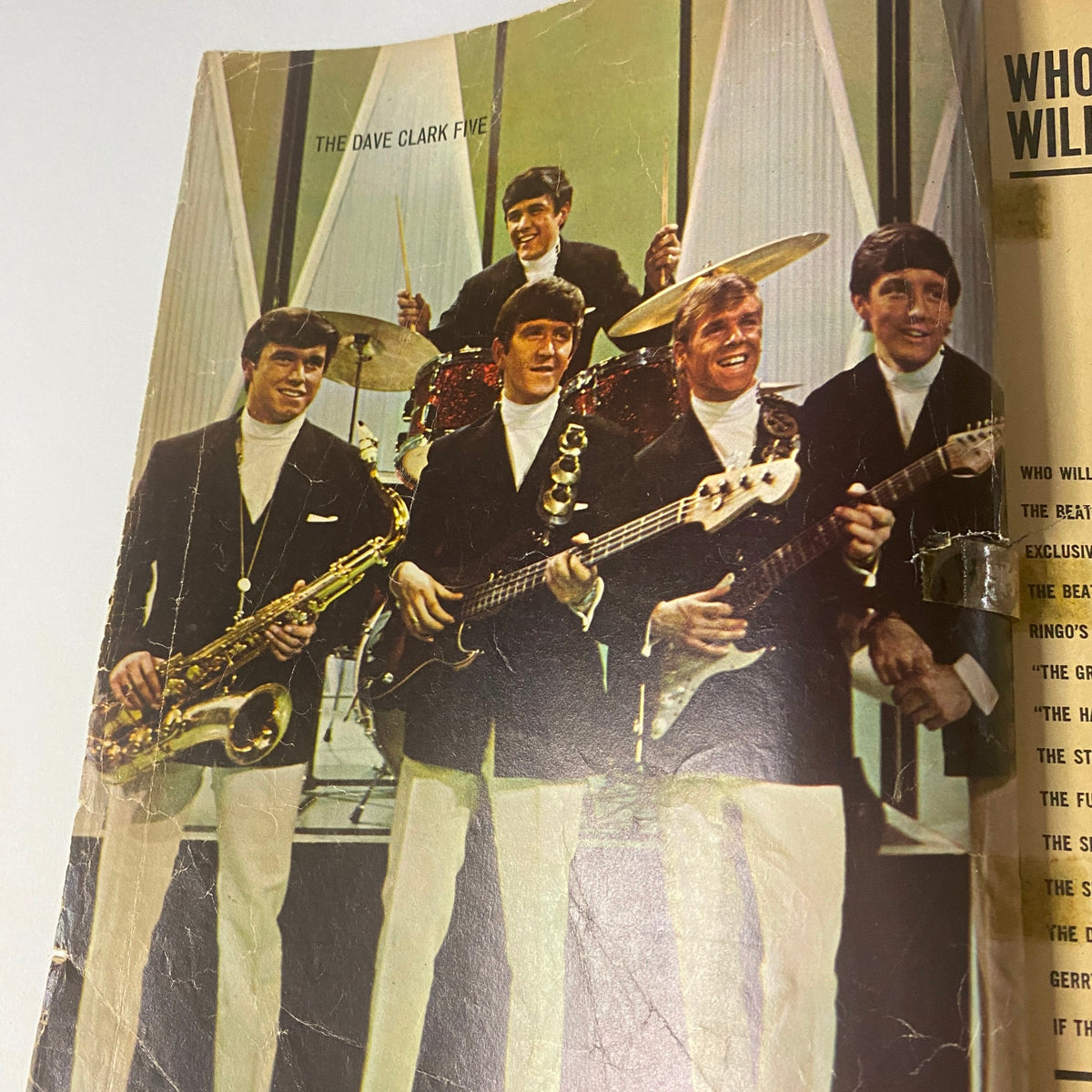 Image of The Dave Clark Five band performing on stage featured in the 1964 magazine 'Who Will Beat The Beatles? The Mersey Sound Hits America'.