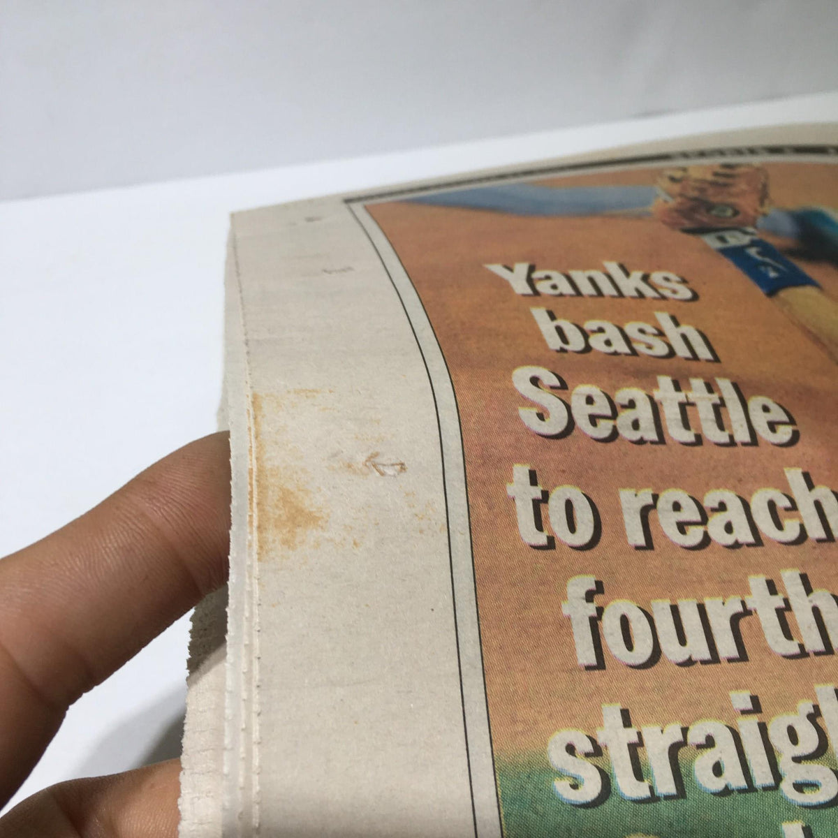 Close-up view of the NY Daily News sports page showing minor staining while focusing on the text about the Yankees' victory.