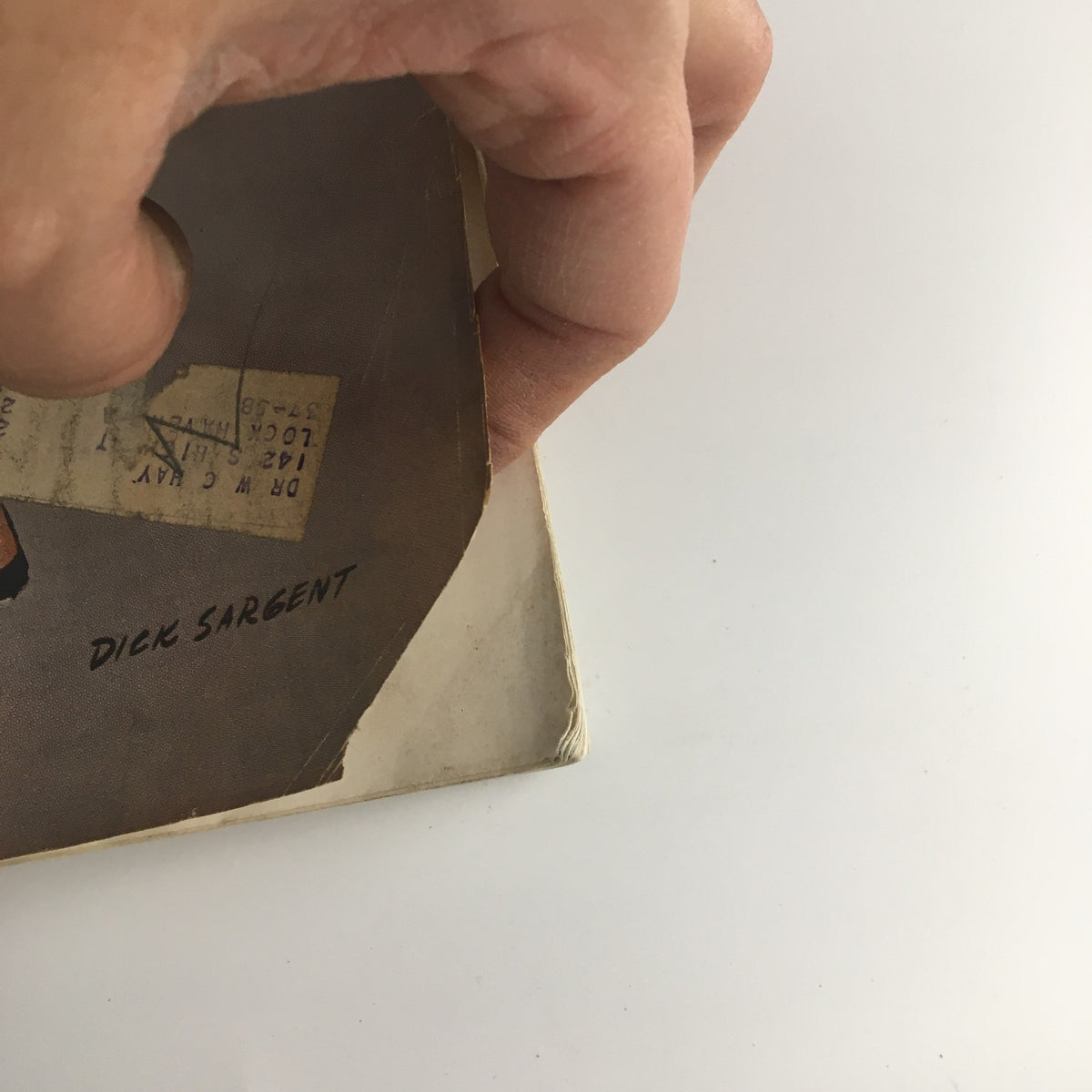 Detail of the corner of The Saturday Evening Post April 14, 1956, showing the signature of the illustrator Dick Sargent and a small address label on the magazine.