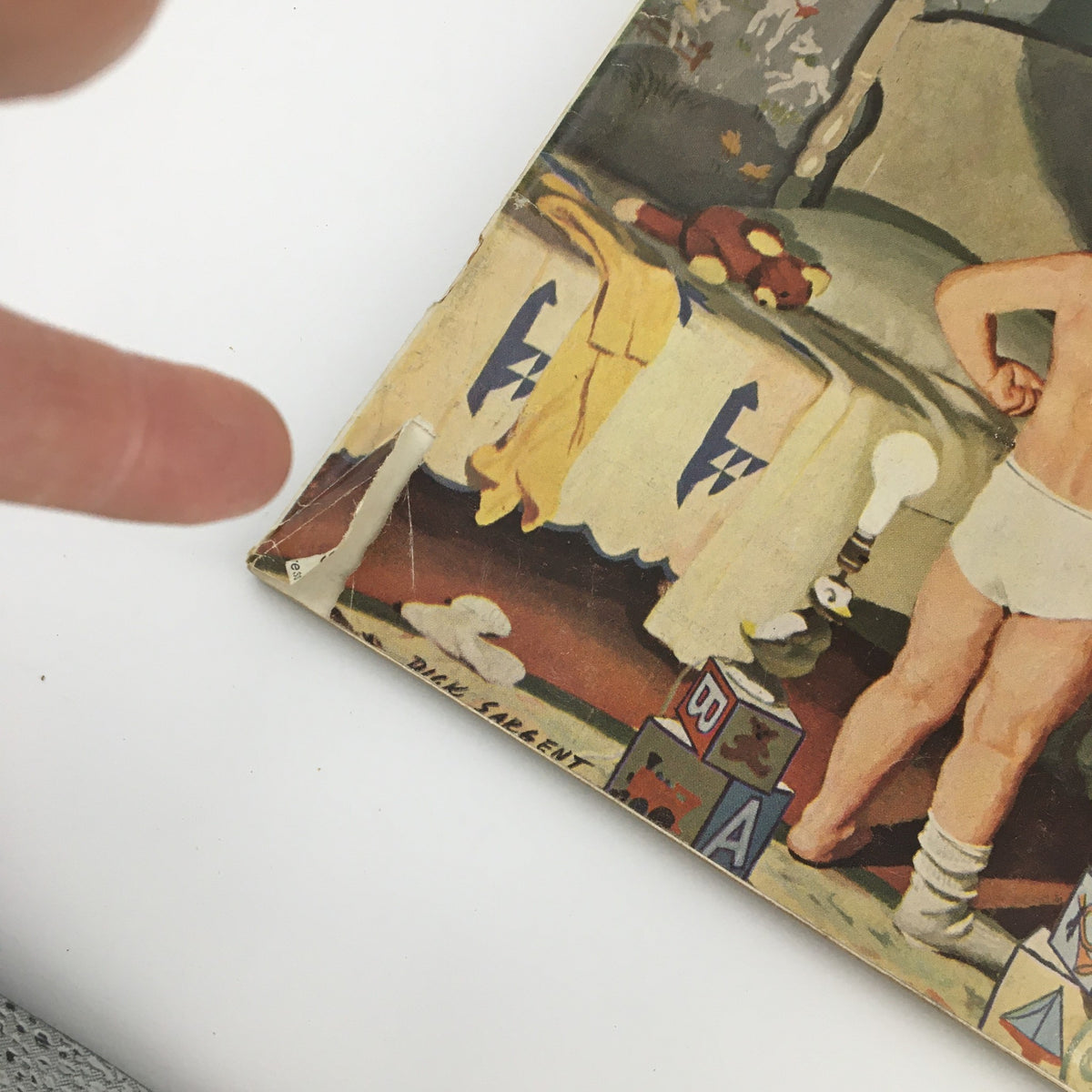 Close-up of the cover edge of The Saturday Evening Post from October 22, 1960, showcasing some wear and tear. The image features a playful scene with a child and toys, highlighting the artwork by Dick Sargent.