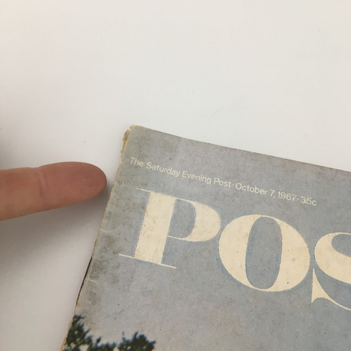 Close-up of the corner of The Saturday Evening Post from October 7, 1967, featuring the magazine title and date with signs of wear, emphasizing its vintage quality.
