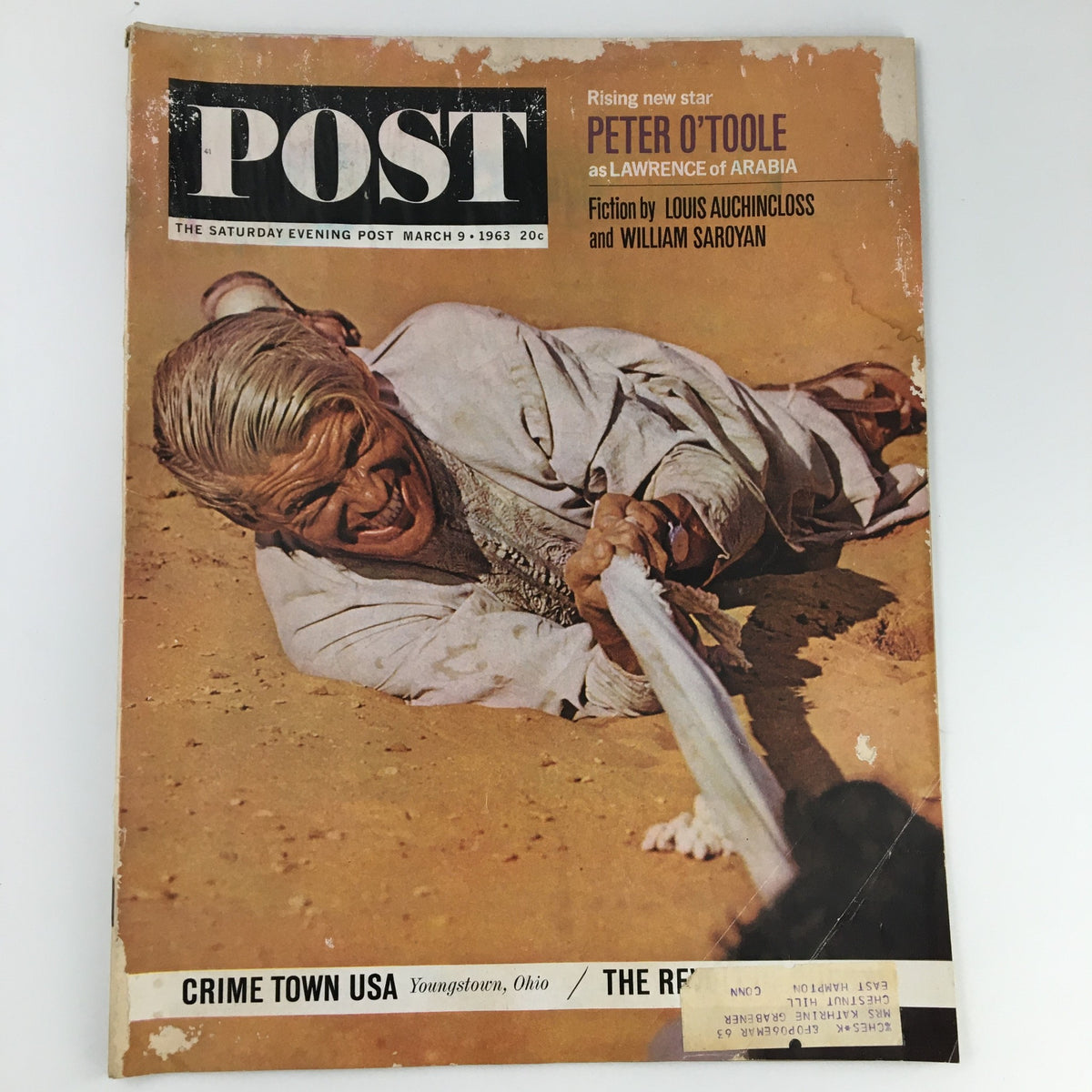 The Saturday Evening Post cover from March 9, 1963 featuring Peter O'Toole as Lawrence of Arabia with a sandy backdrop and action scene. Highlights the article 'Crime Town USA' and includes fiction by Louis Auchincloss and William Saroyan.