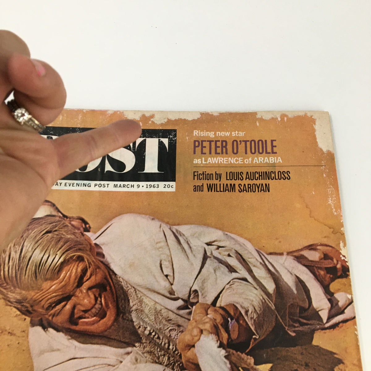 A close-up of The Saturday Evening Post March 9, 1963 cover showing Peter O'Toole as Lawrence of Arabia, with visible wear and hand pointing at the title and details.