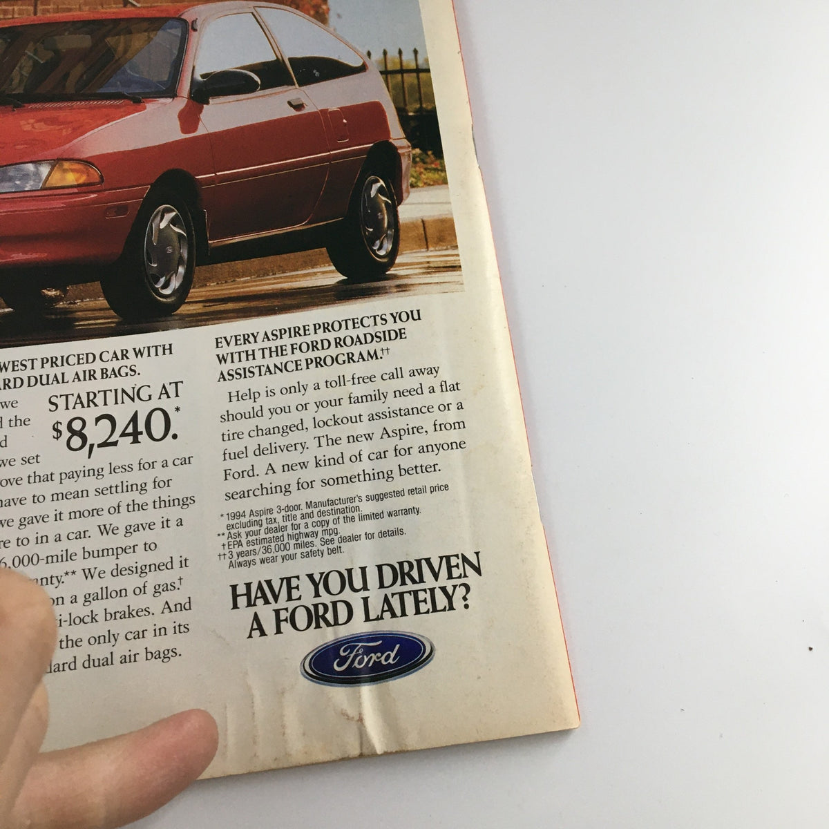 Detailed view of the Ford Aspire advertisement from a 1994 magazine, emphasizing features and roadside assistance program.